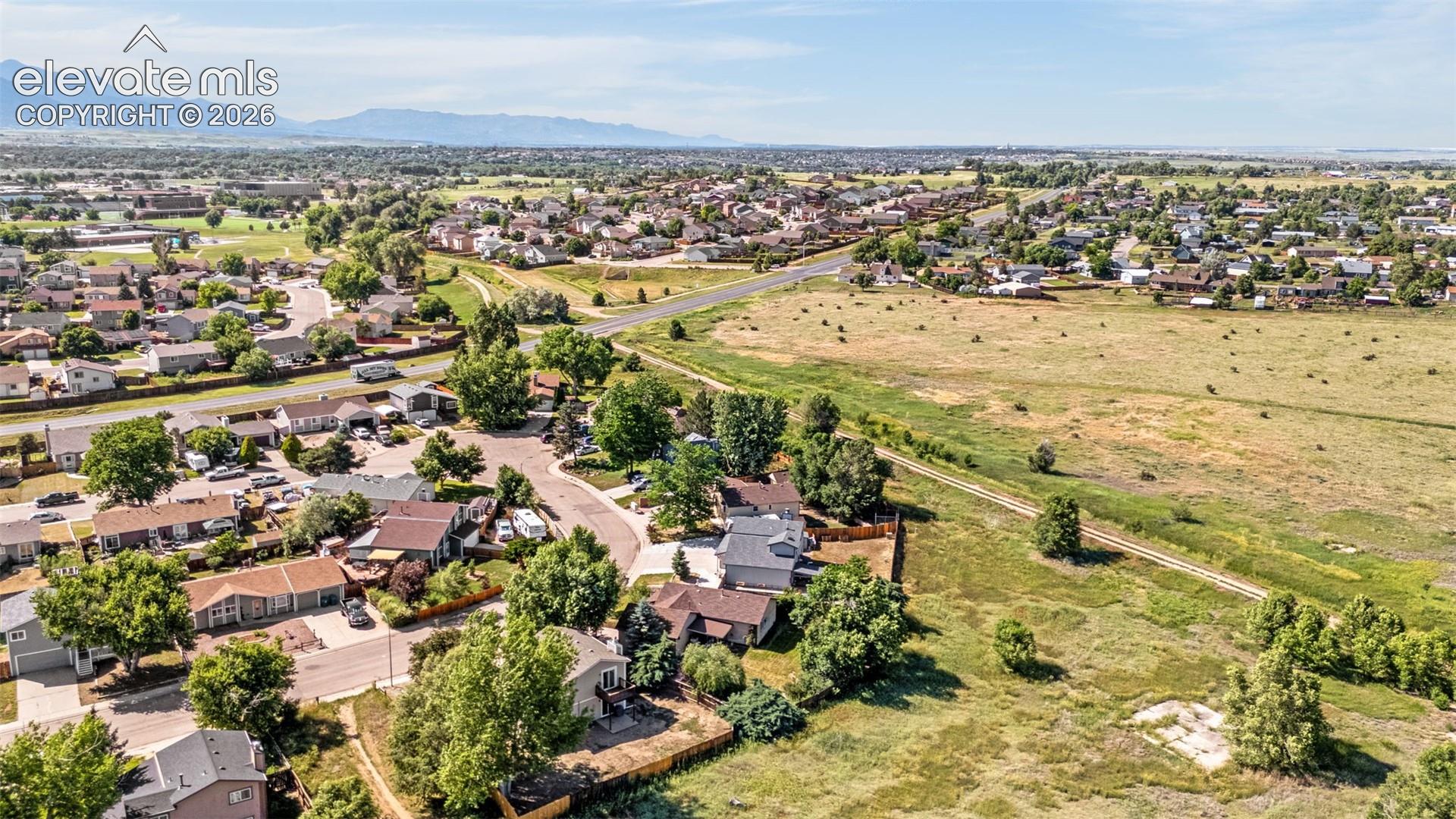 Aerial perspective featuring extensive open land, established trees, and mountain backdrop