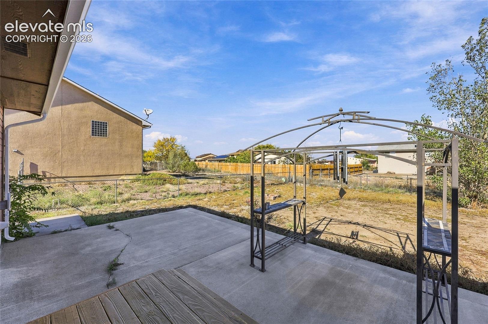 Concrete patio featuring wood decking and metal perimeter fencing
