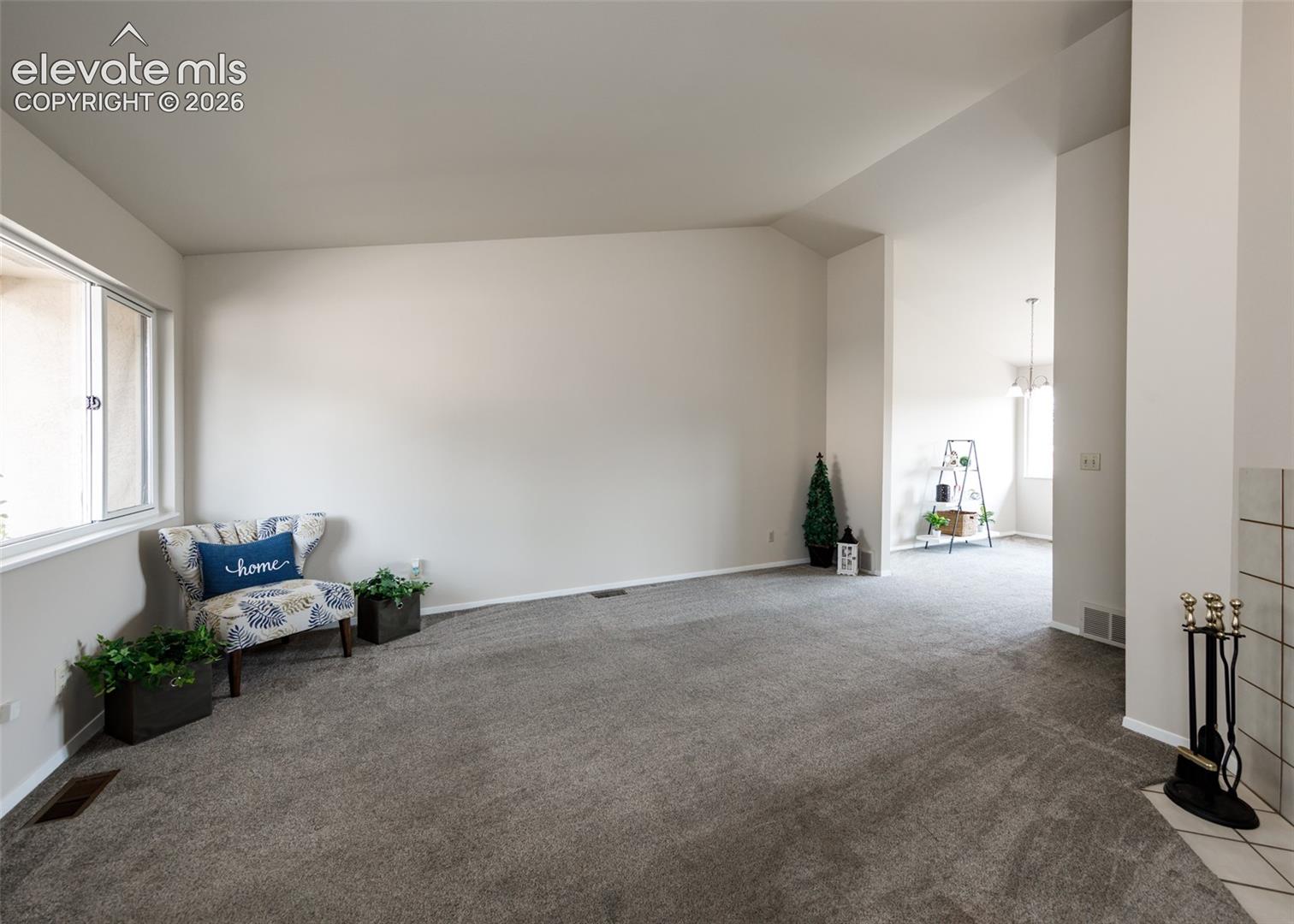 Vaulted ceilings with recessed lighting, large window with natural light, neutral wall colors, and grey carpeting