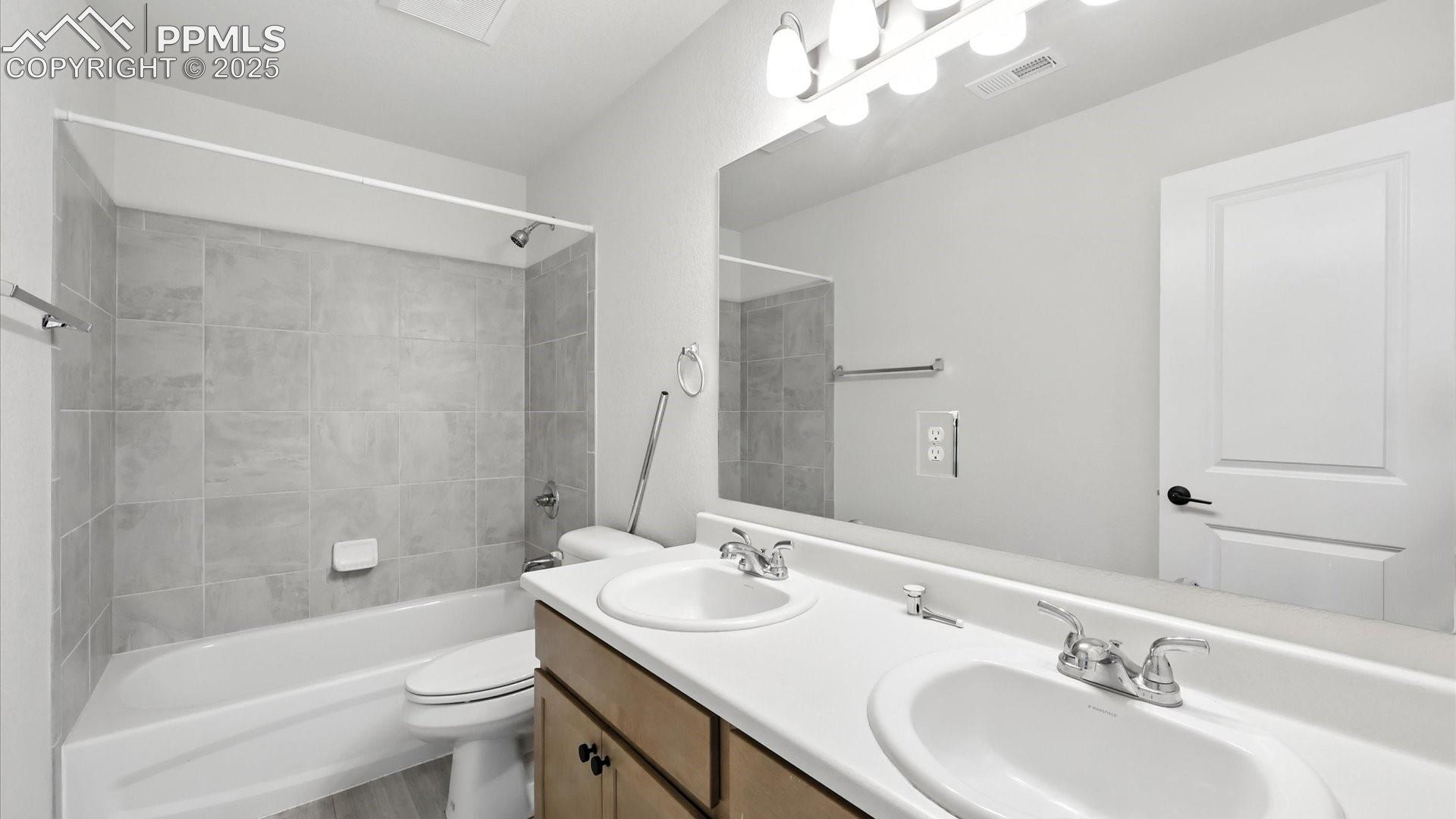 Upper Level Full Hall Bathroom with dual sink vanity, mirror, and tiled tub/shower.