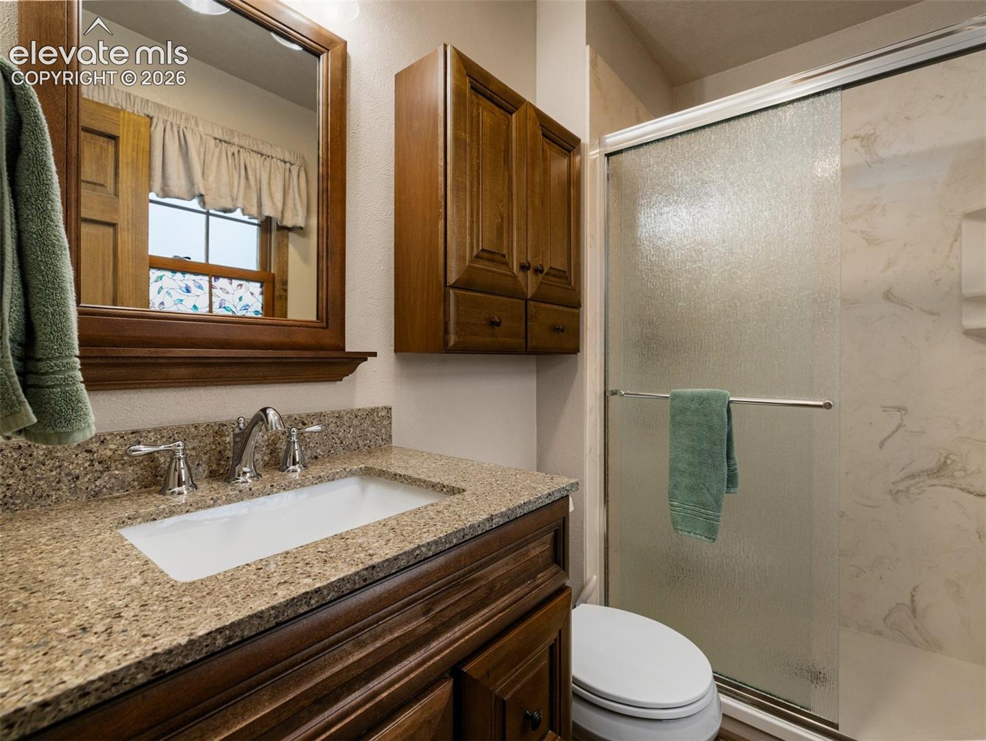Wood-finish vanity with an integrated rectangular sink, granite-style countertop, and polished chrome faucet