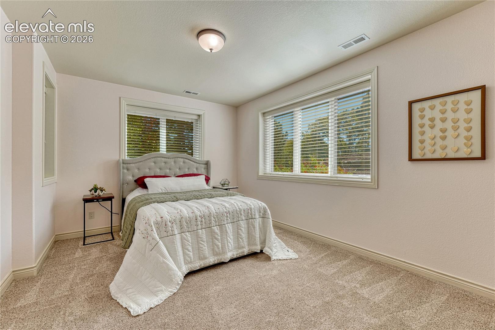 Neutral-toned wall paint, plush carpeting, recessed ceiling lighting, and large windows with horizontal blinds