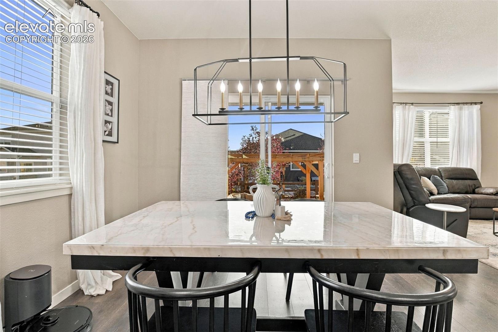 Dining area featuring wood-finish flooring, a contemporary six-light geometric chandelier, and sliding glass doors with access to the exterior