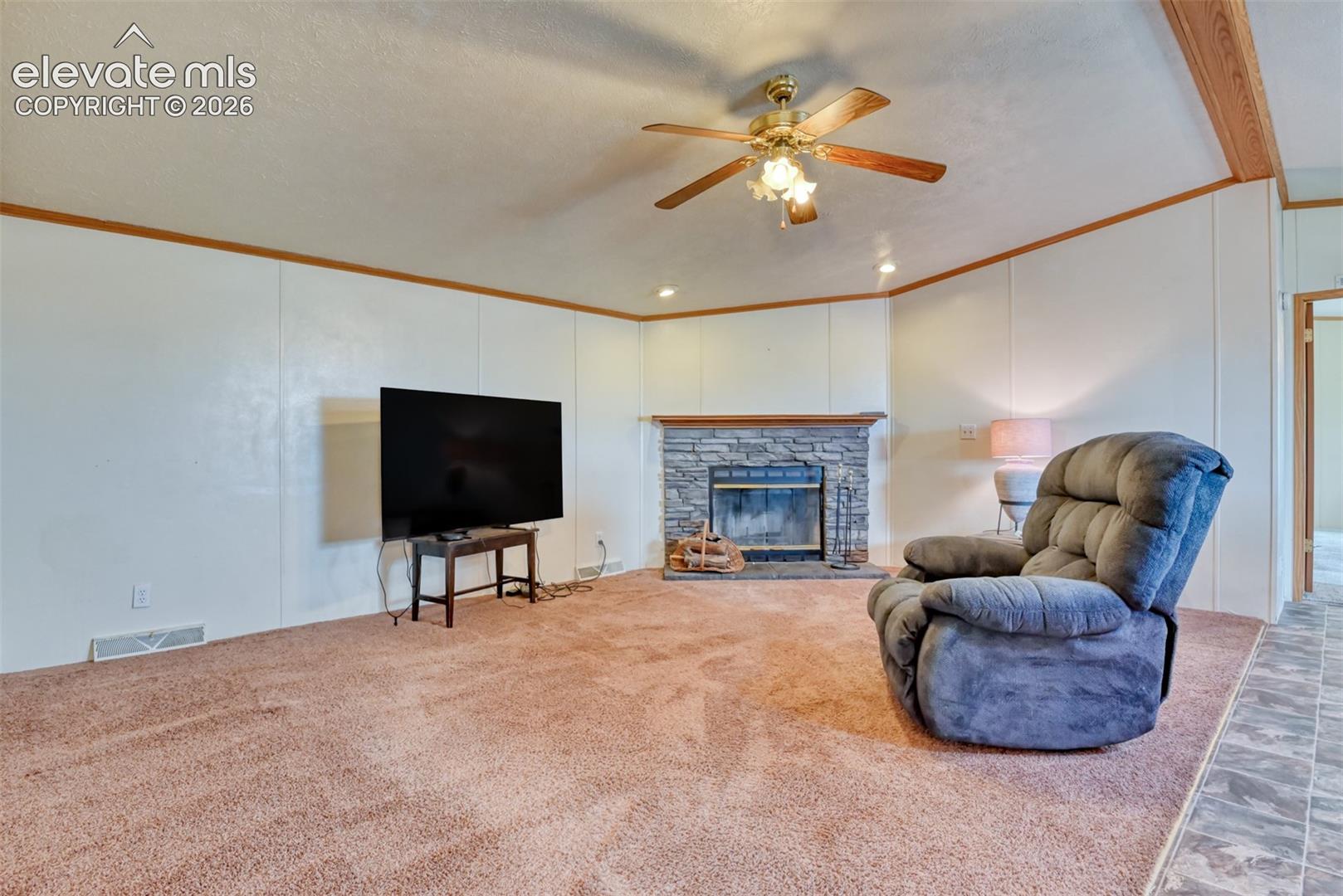 Living area featuring a stone-clad fireplace with a dark insert, a ceiling fan with integrated lighting, and recessed ceiling lights