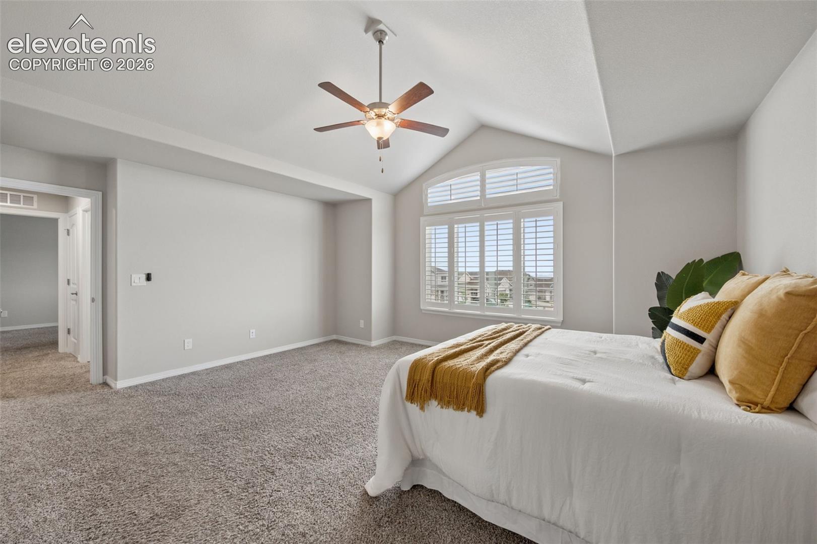 Vaulted ceiling with a ceiling fan, arched window with plantation shutters, and light grey wall finishes