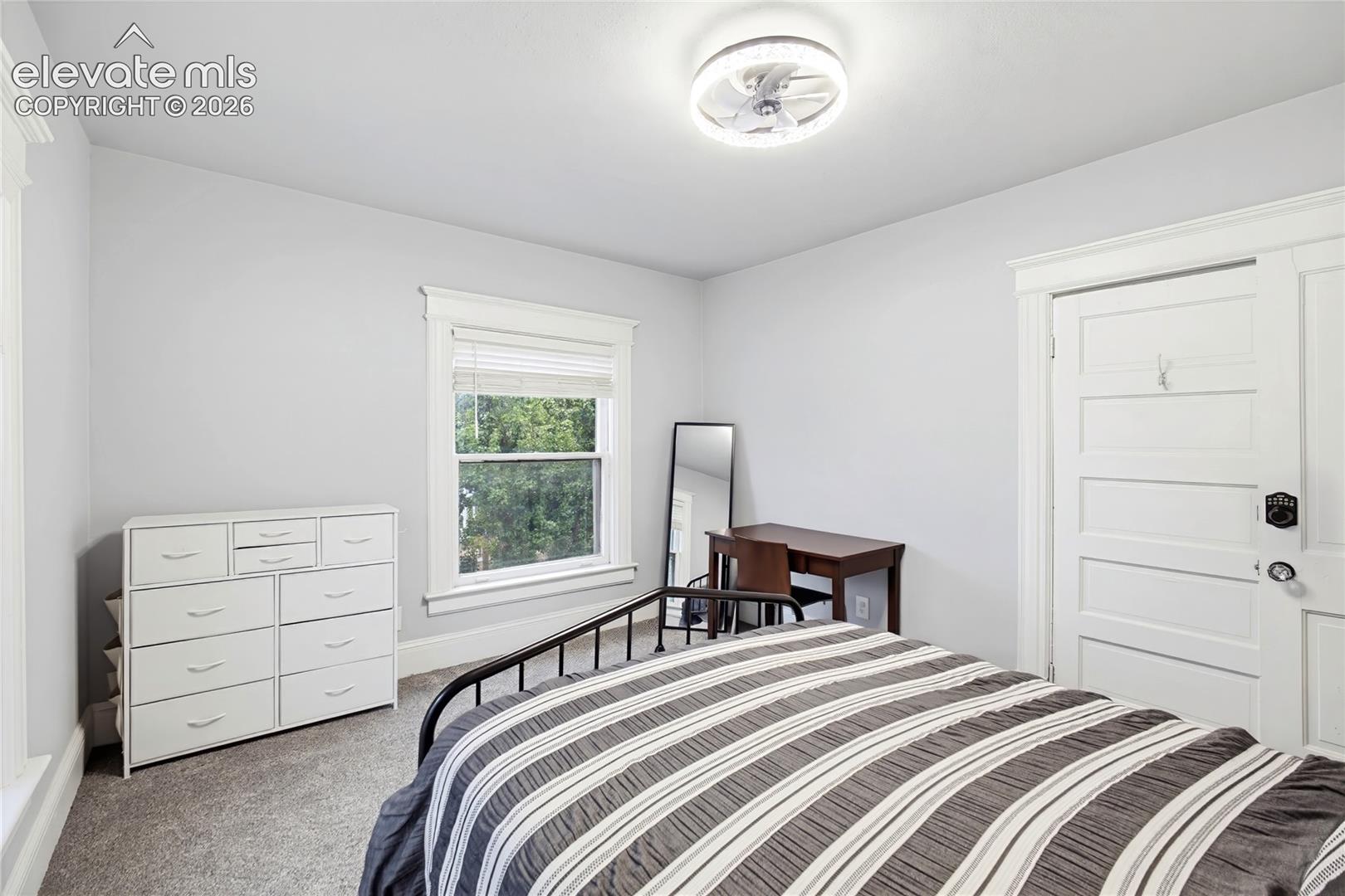 Recessed ceiling fan with integrated lighting, window with white blinds, neutral wall paint, and gray carpeting