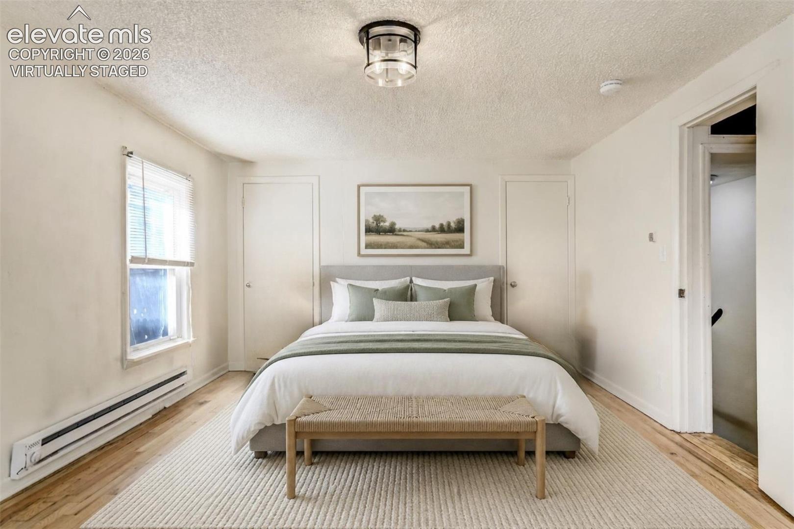 Virtually Staged..Neutral walls, wood-finish flooring, central overhead lighting fixture, and a window with white horizontal blinds