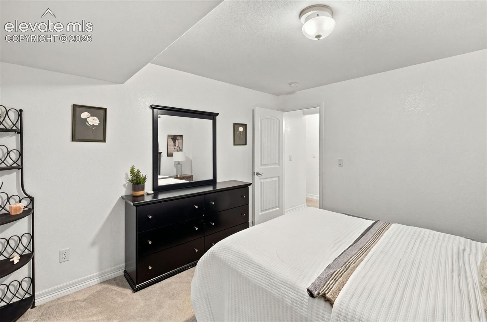 Neutral wall palette featuring textured finish, wall-to-wall carpeting, and a single-panel arch-top interior door with brushed metal hardware, complemented by a flush-mount circular ceiling fixture