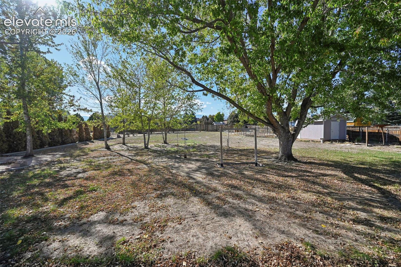 Expansive yard featuring mature trees and a privacy fence