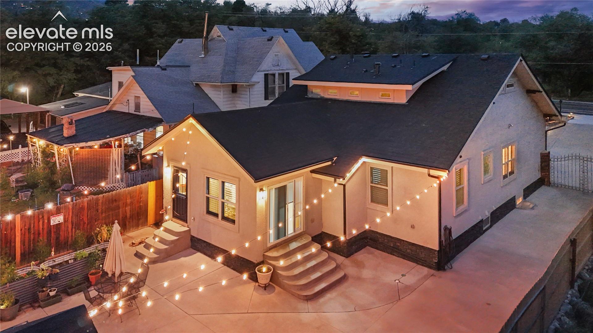 Exterior featuring stucco siding, a dark shingle roof, and multiple window openings