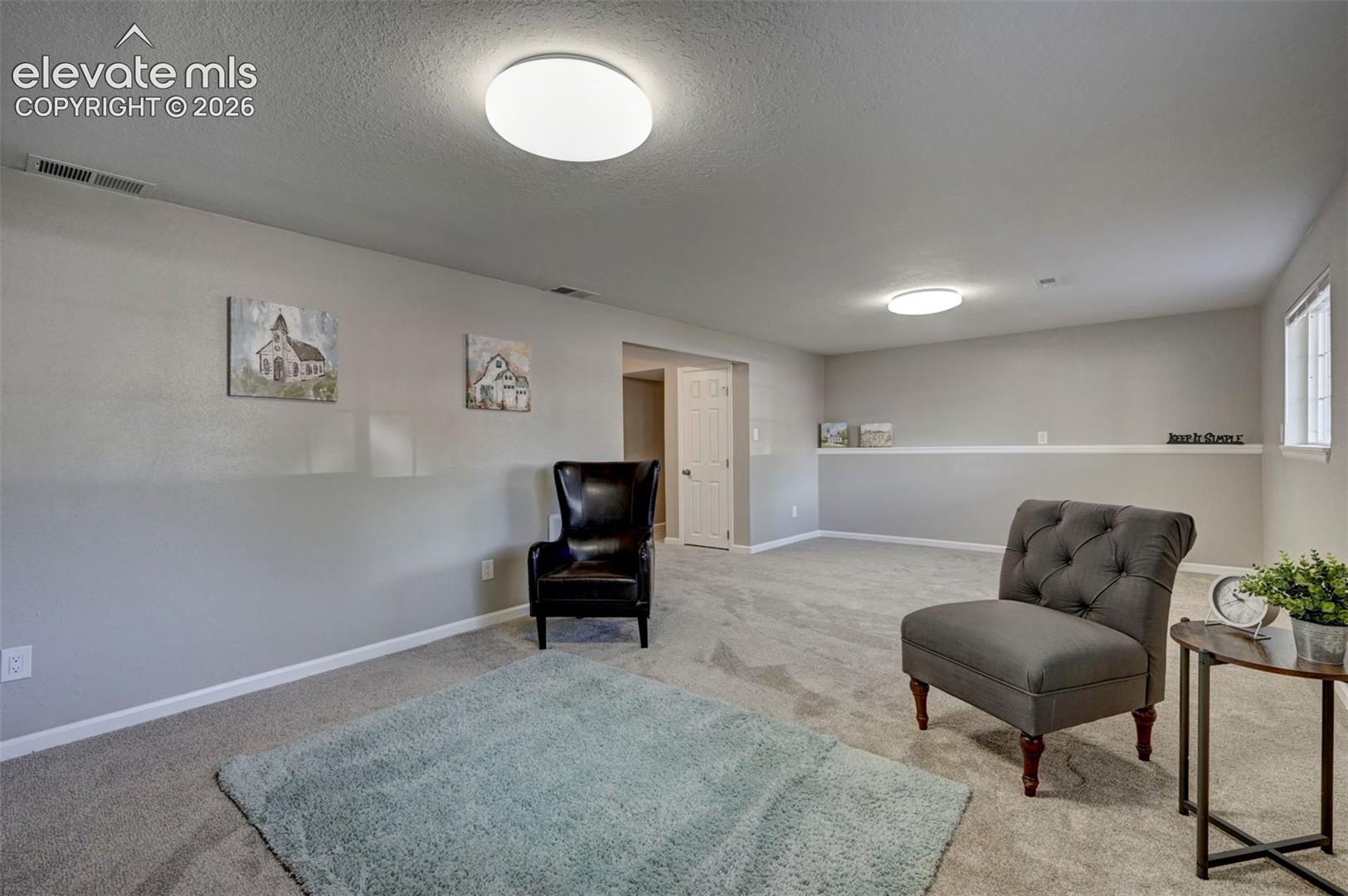 Neutral-toned interior space featuring wall-to-wall carpeting, flush-mount circular lighting, a chair rail, and a solid-core interior door