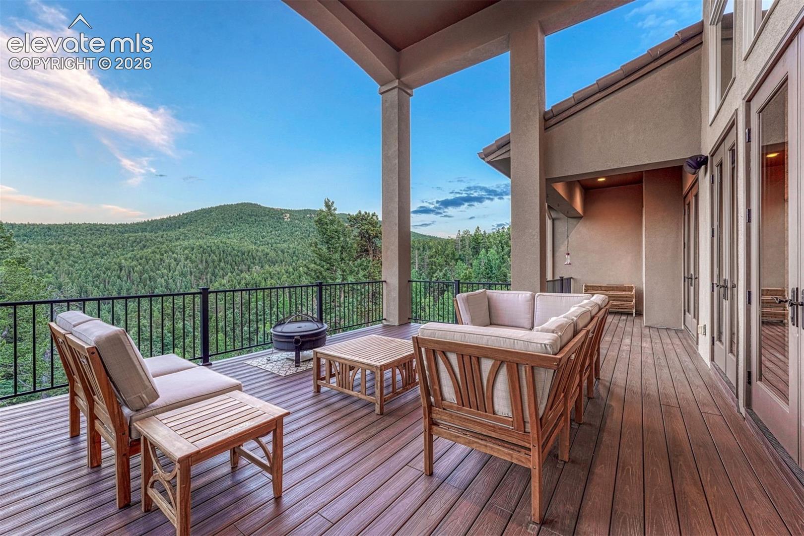 Expansive outdoor deck featuring wood-finish flooring, a black metal railing, and multiple sets of French doors
