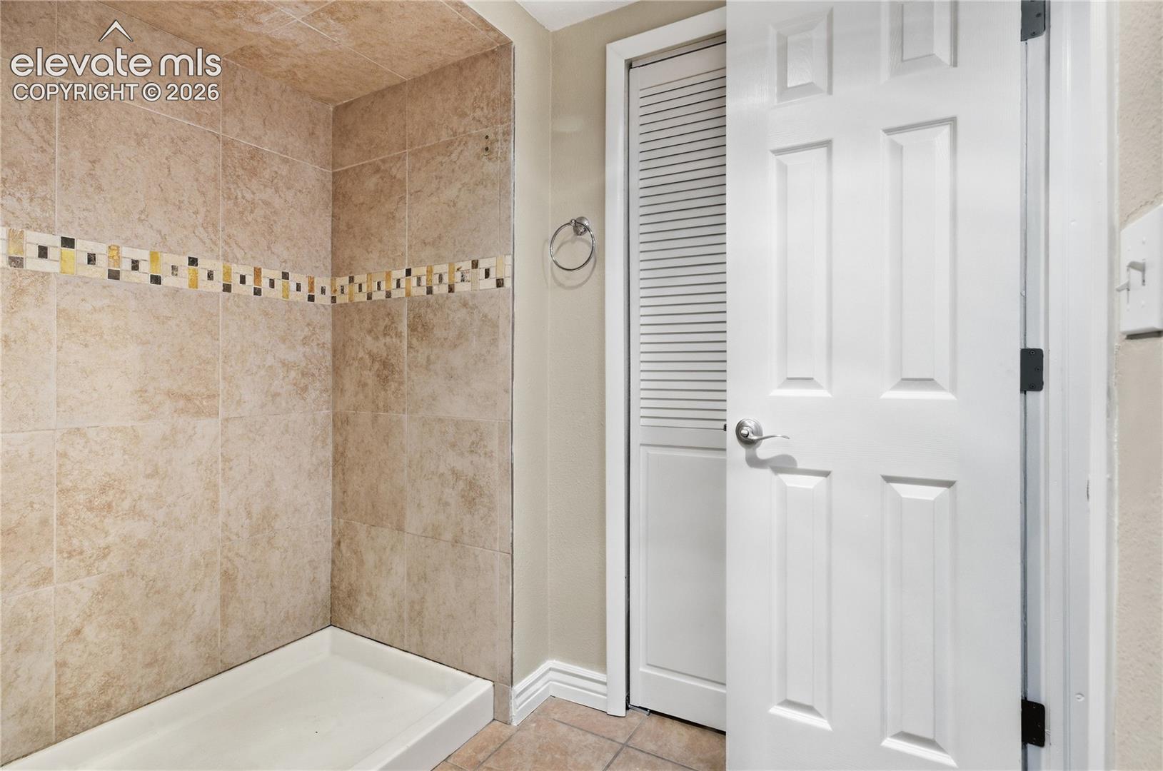 Tiled shower surround with decorative mosaic accent band