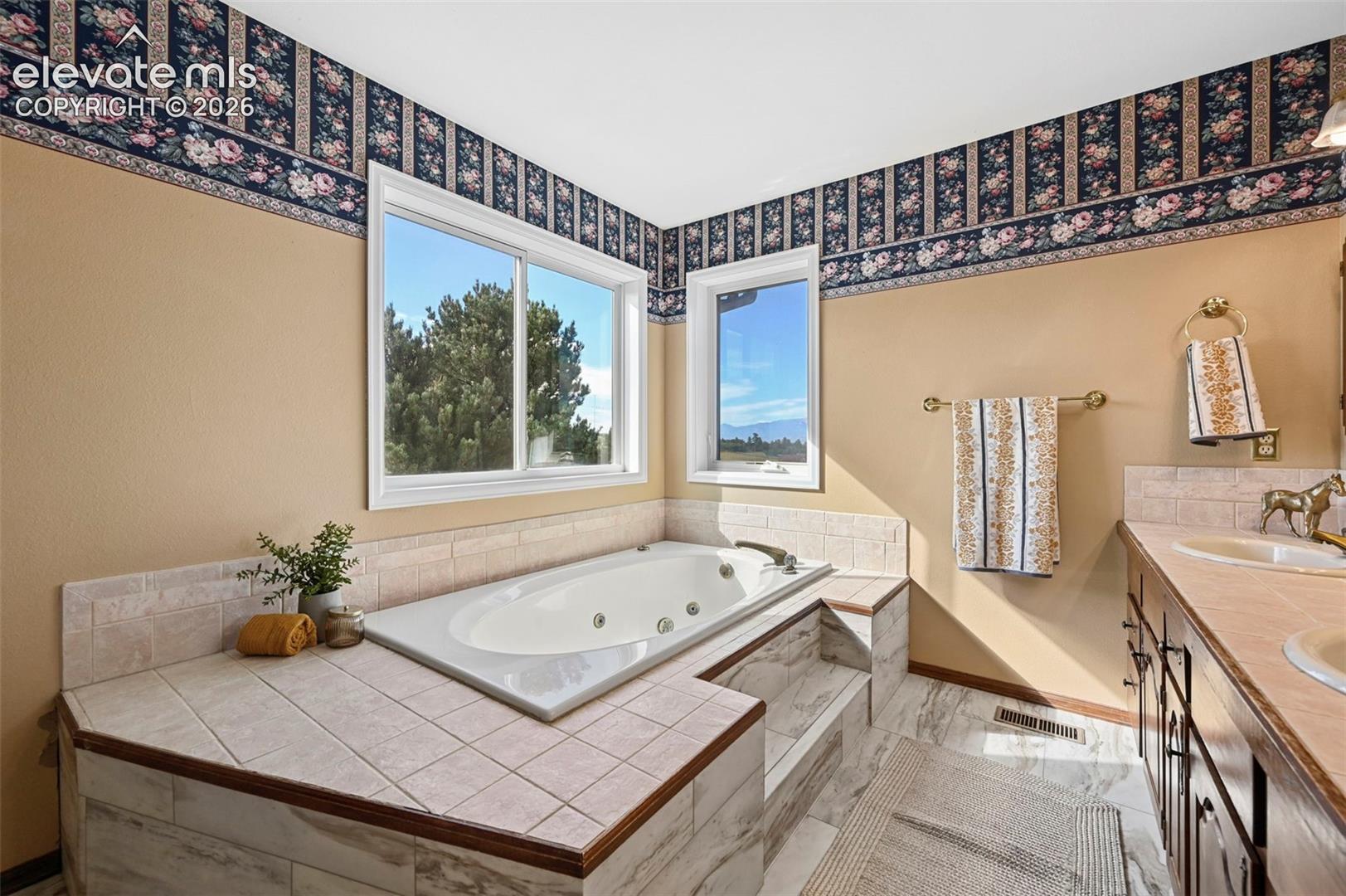 Built-in jetted tub with tiled surround and double vanity.