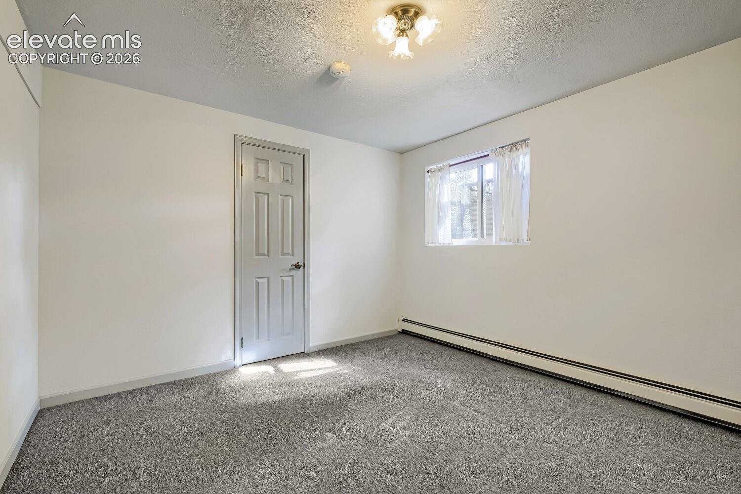 Neutral wall tones with gray carpet flooring, multi-pane window, and a paneled interior door