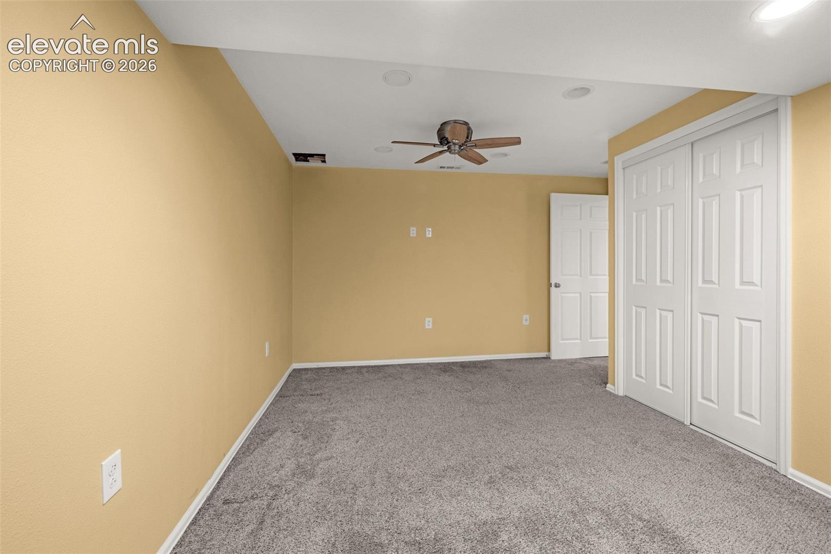 Neutral-toned room featuring wall-to-wall carpeting, recessed ceiling lighting, a ceiling fan, and double-panel sliding closet doors