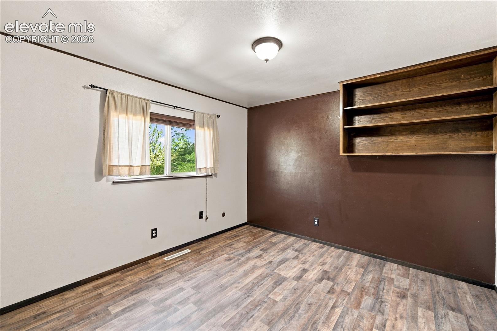 Built-in shelving, wood-finish flooring, and a semi-flush mount ceiling light fixture