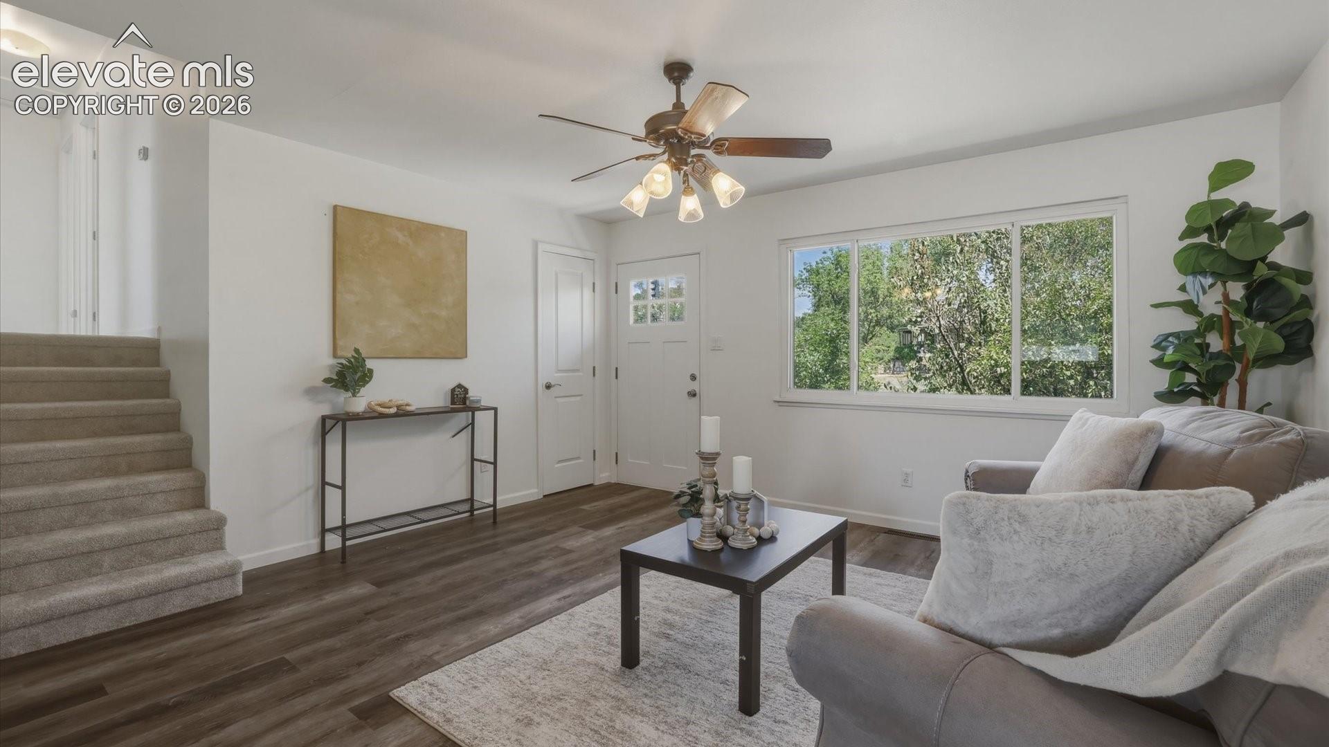 The bright living room is filled with natural light and includes a ceiling fan.