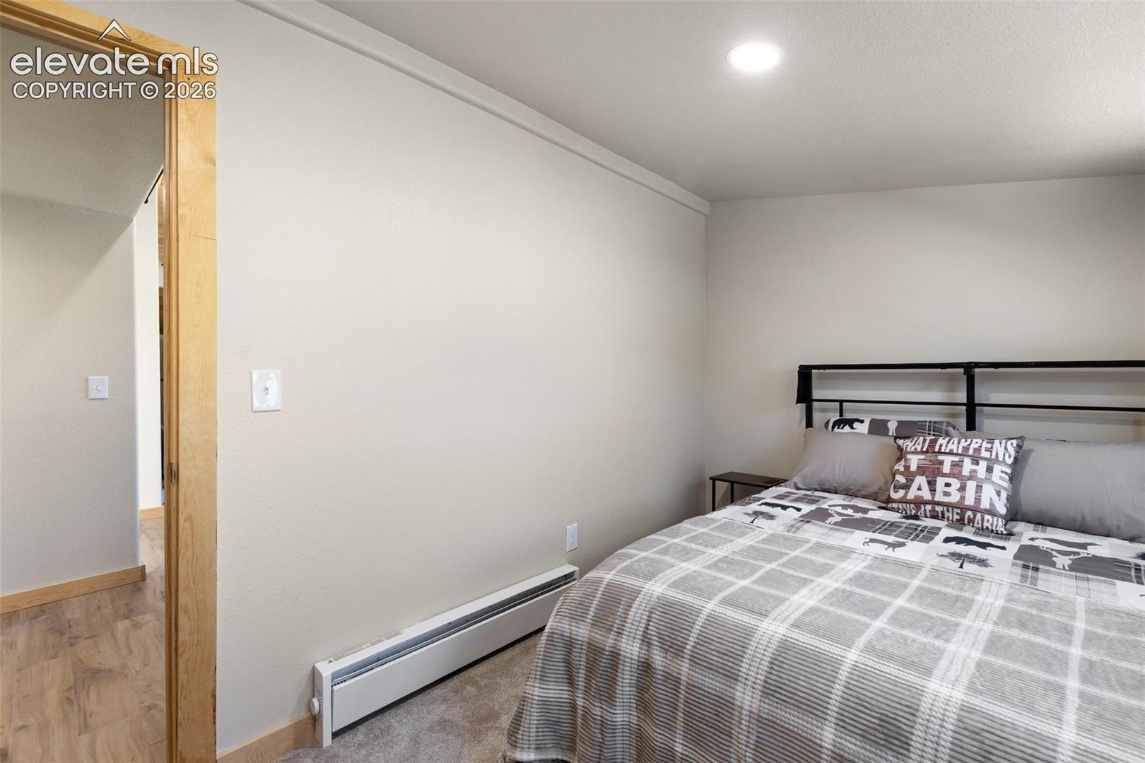 Neutral-toned interior space featuring light-colored wall paint, recessed ceiling lighting, and natural wood door casing