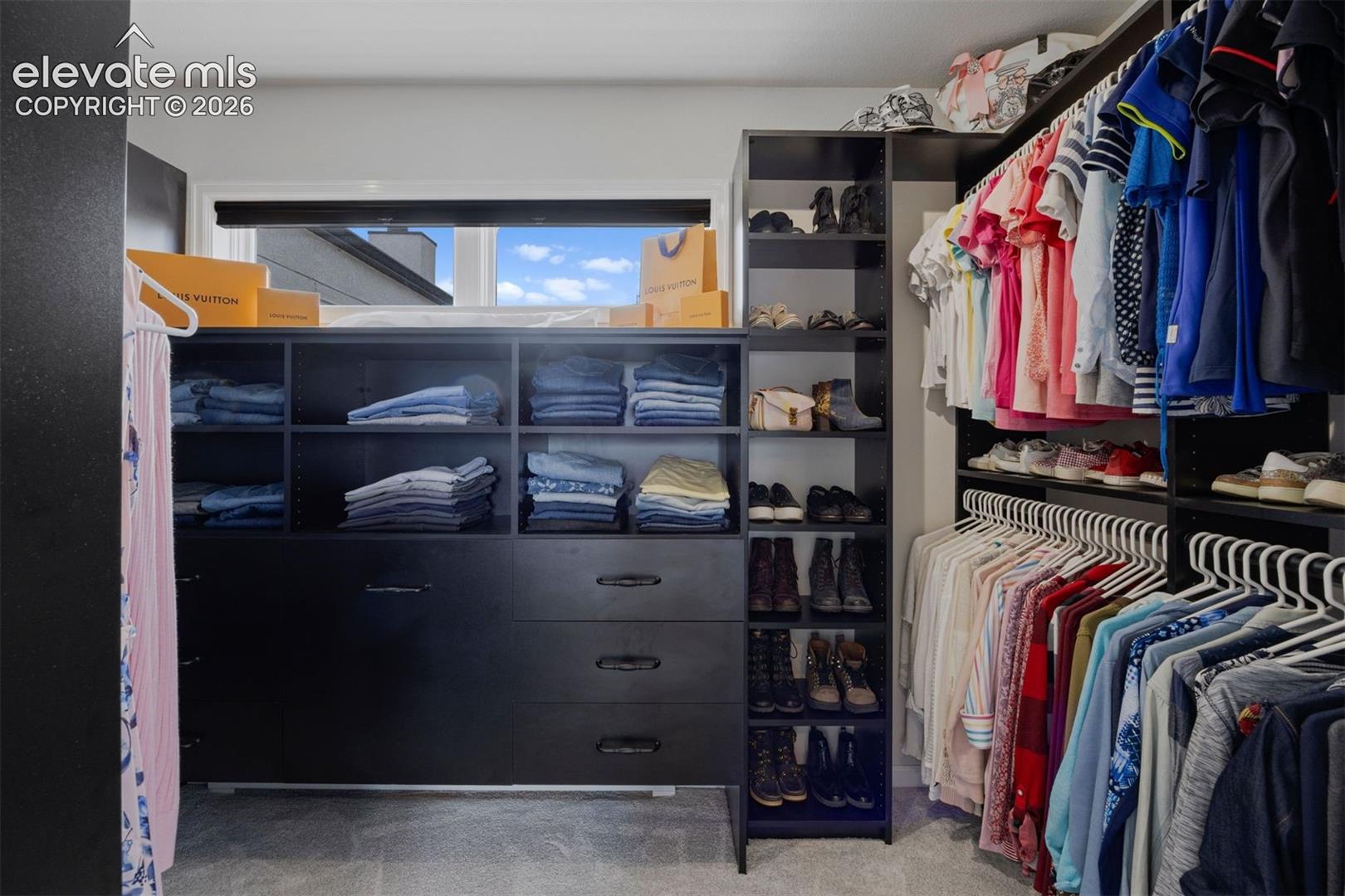 Large walk-in closet with custom built-in organization system — shelving, drawers, hanging rods, and shoe storage.