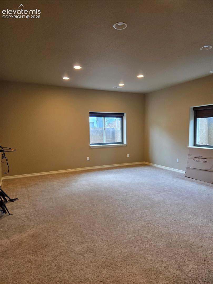 open- Spacious room featuring neutral carpeting, recessed lighting, and two windows with dark blinds