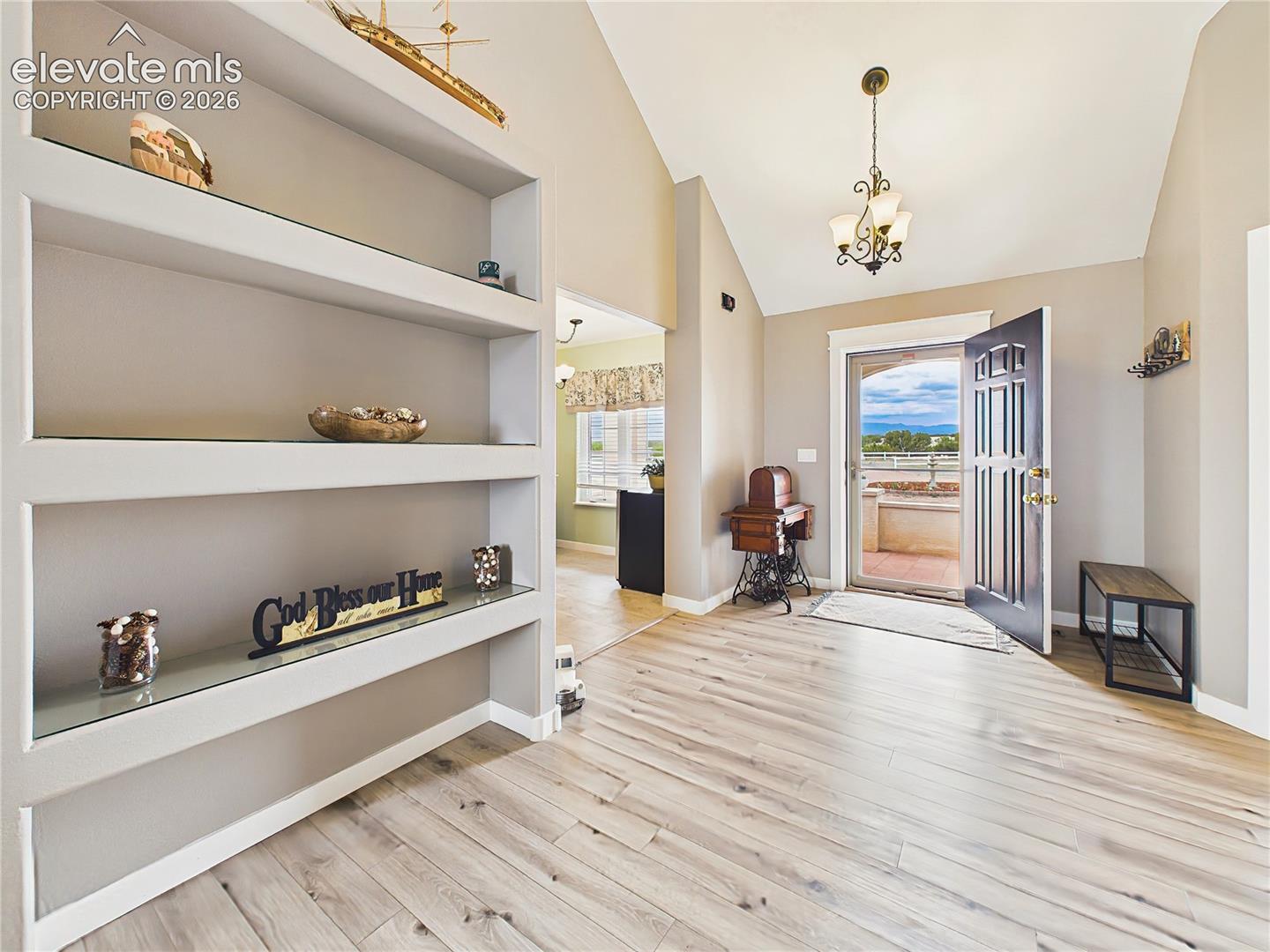 Welcoming foyer features vaulted ceilings, updated flooring, and custom built-in display shelving that adds both style and functionality.