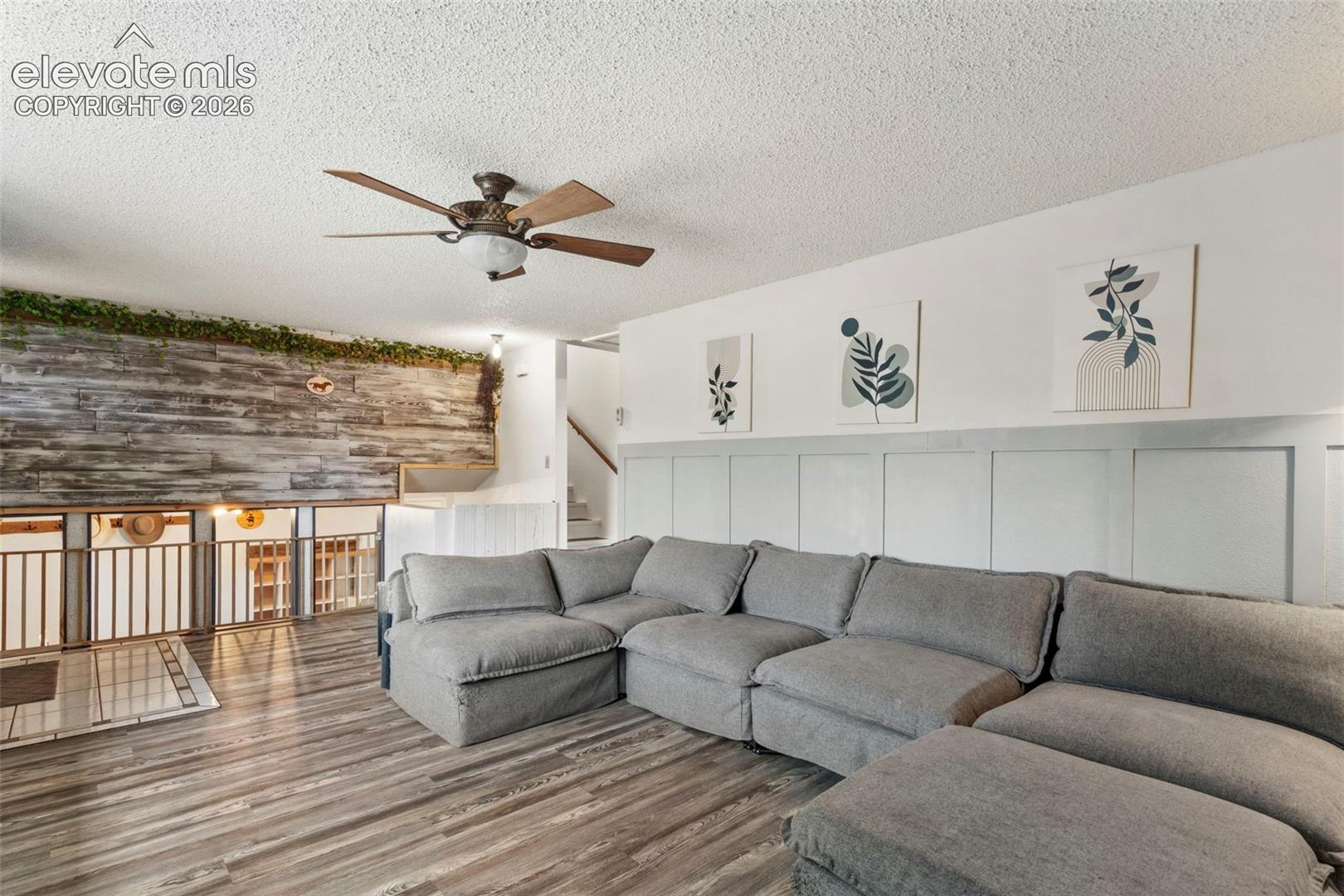 Spacious living area featuring wood-finish flooring and a textured accent wall