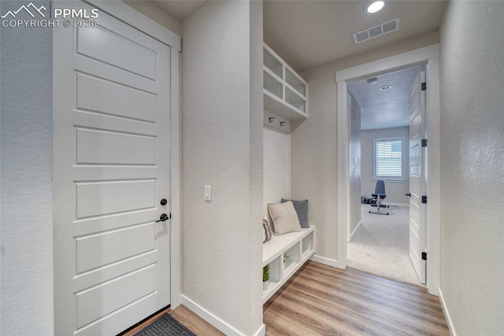 Mudroom with light wood-style flooring and a textured wall