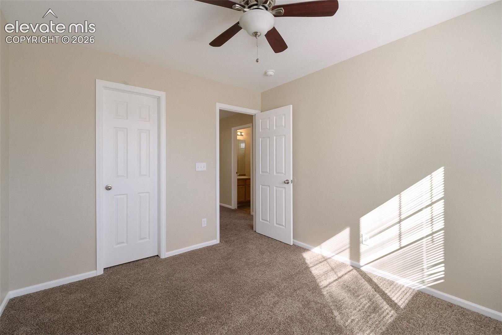 Neutral interior featuring wall-to-wall carpeting, six-panel interior doors, and a ceiling fan with integrated lighting