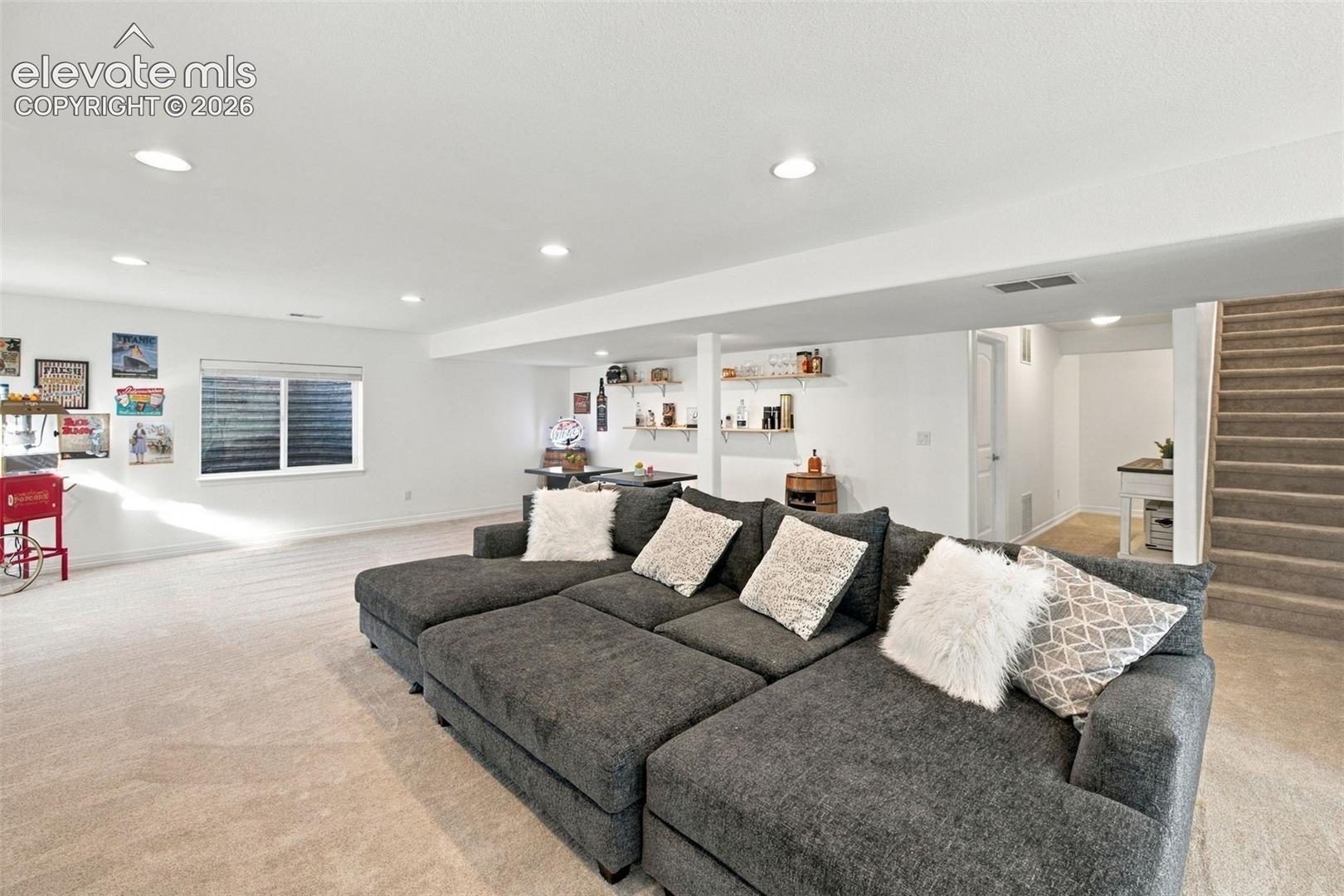 Finished interior space featuring recessed lighting, wall-to-wall carpeting, built-in wall shelving, and a window with a window well