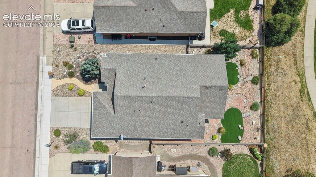 Durable shingle roofing, concrete driveway, and rock landscaping with artificial turf accents