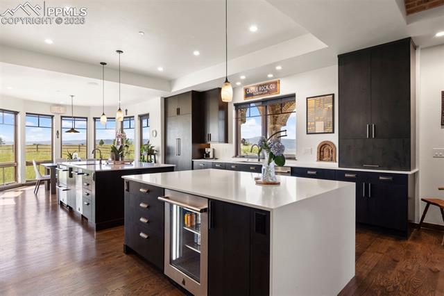 Designer kitchen with dual quartz islands, floor-to-ceiling cabinetry, JennAir appliances, and mountain views beyond.