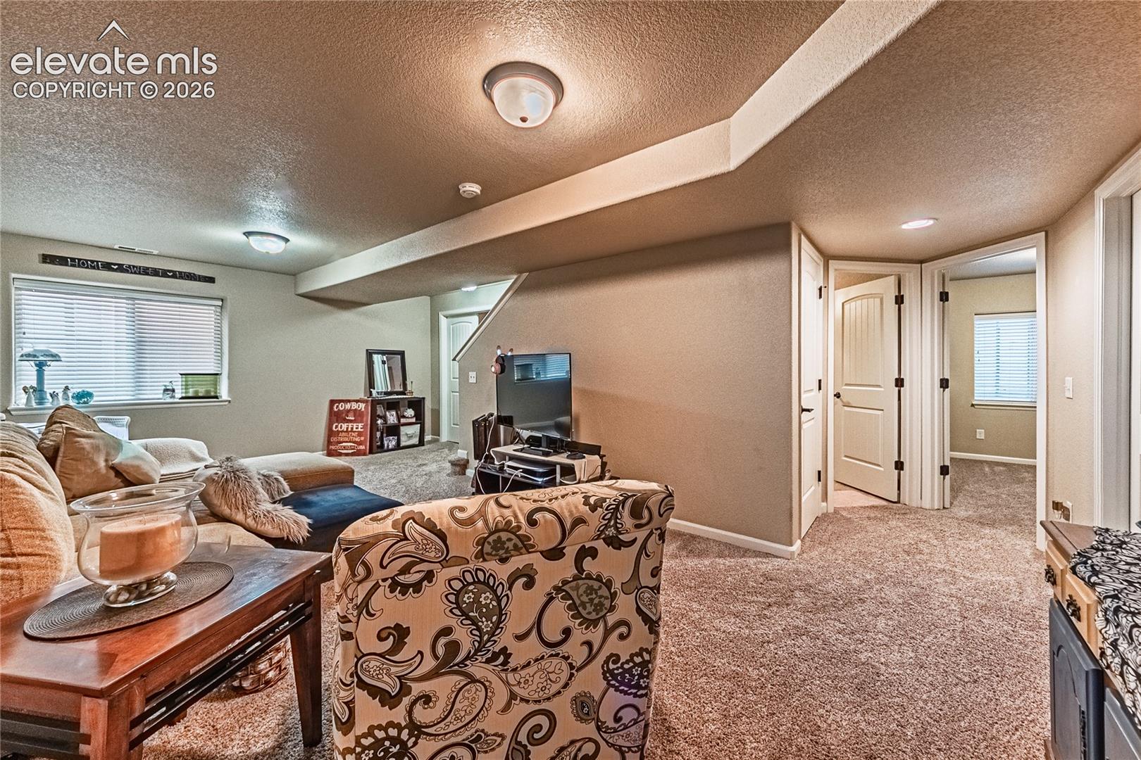 Carpeted living area with a textured ceiling and baseboards