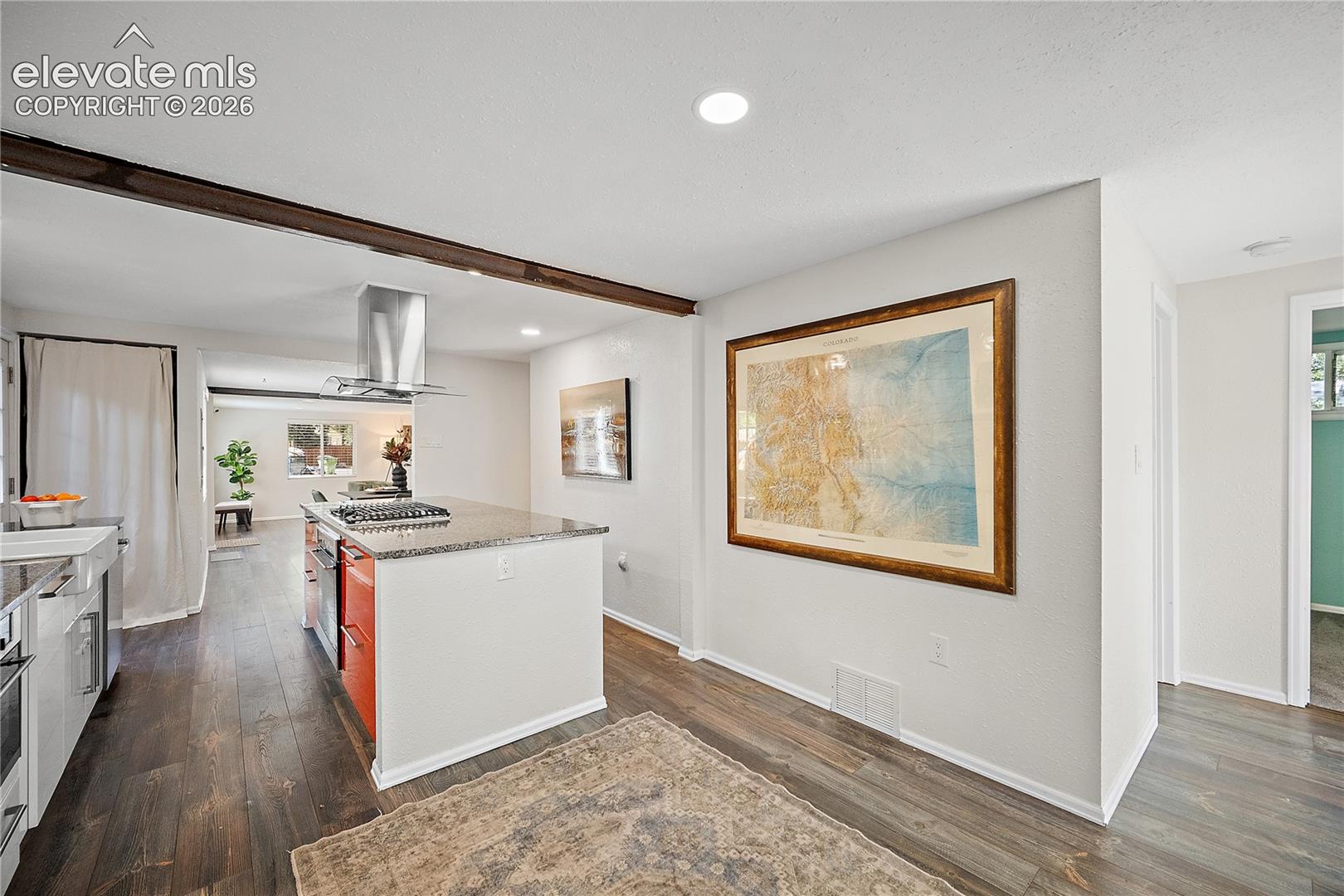 Kitchen island featuring a built-in gas range with a stainless steel range hood, granite-style countertop, and red lower cabinetry