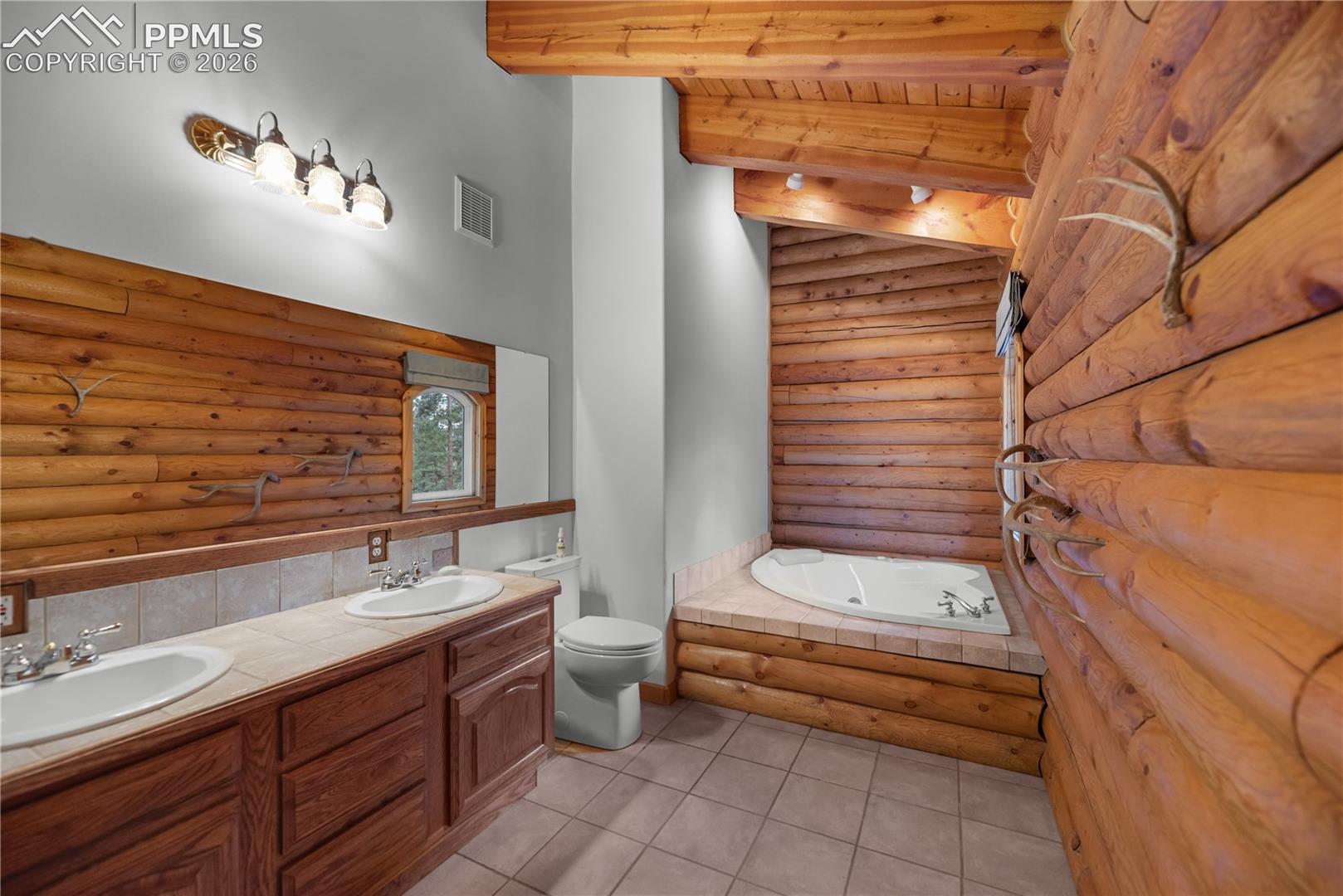 Full bath with log walls, a garden tub, double vanity, tile patterned flooring, and a wood ceiling with exposed beams