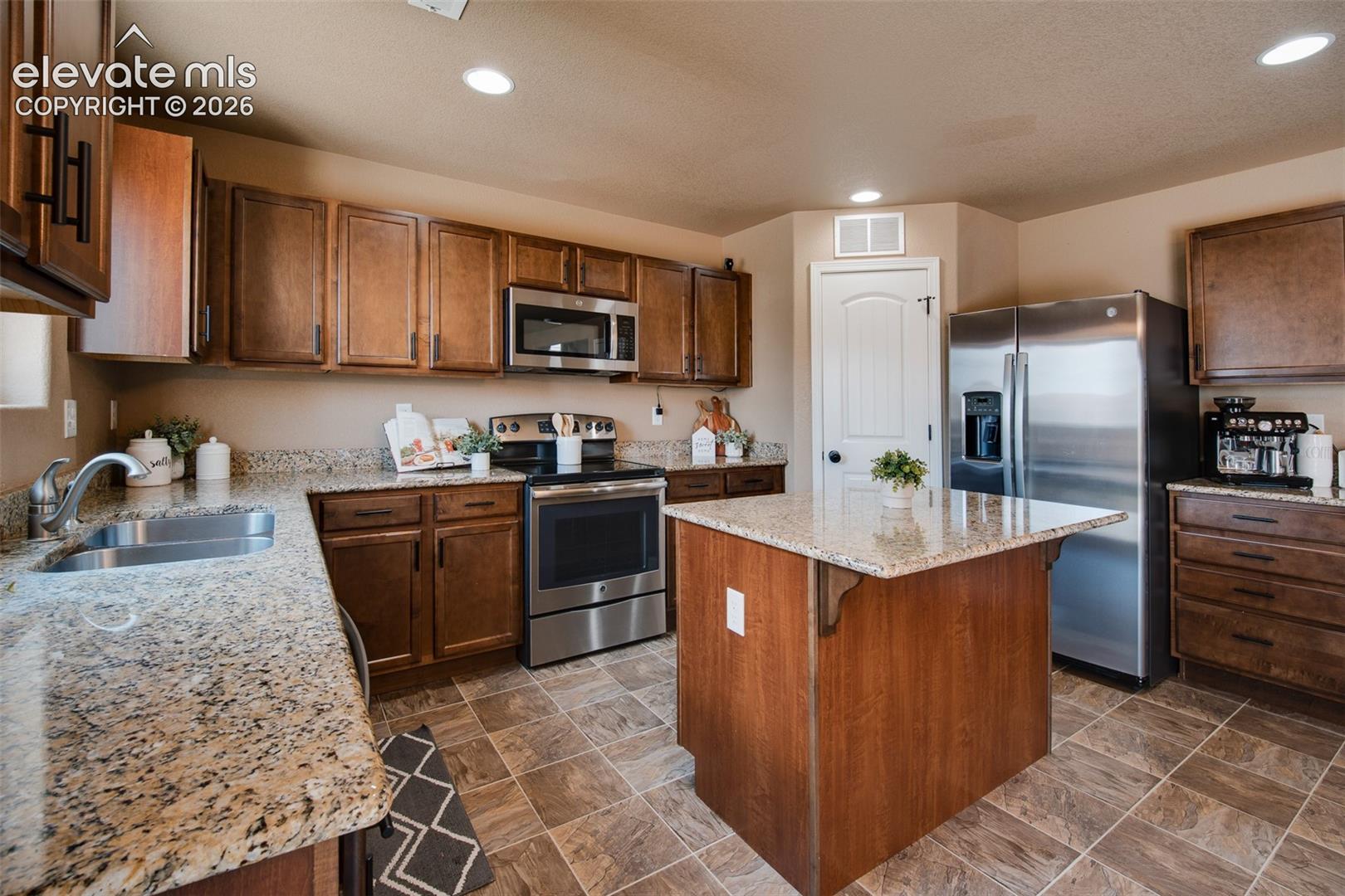 Stainless steel appliances include a smooth top range oven, microwave, dishwasher, and side by side refrigerator.