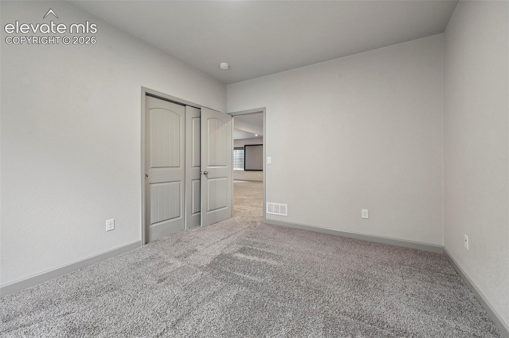 Neutral wall-to-wall carpeting, grey-toned interior paint, and paneled closet doors