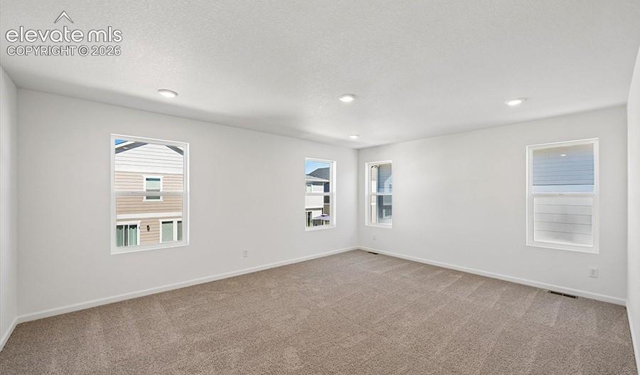 Interior space featuring neutral wall-to-wall carpeting, recessed ceiling lighting, and four dual-pane windows
