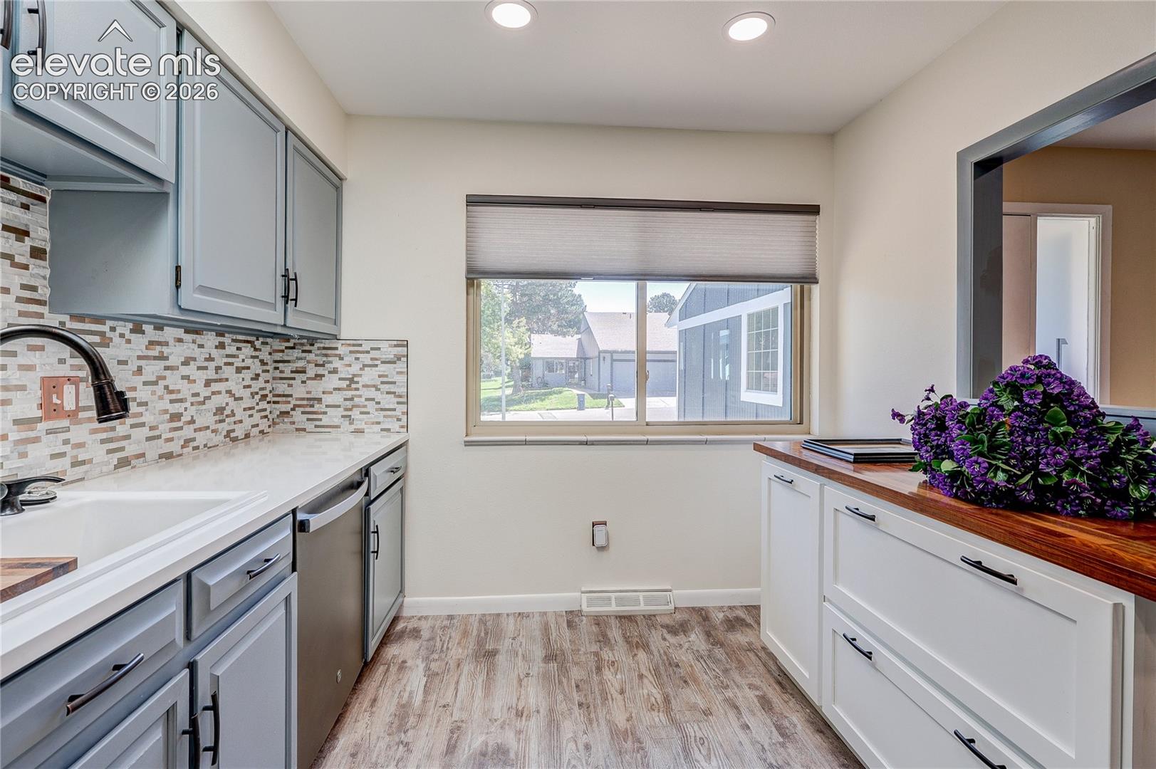 Kitchen featuring light blue cabinetry, stone-composite countertops, a wood-surface counter, mosaic tile backsplash, and recessed lighting