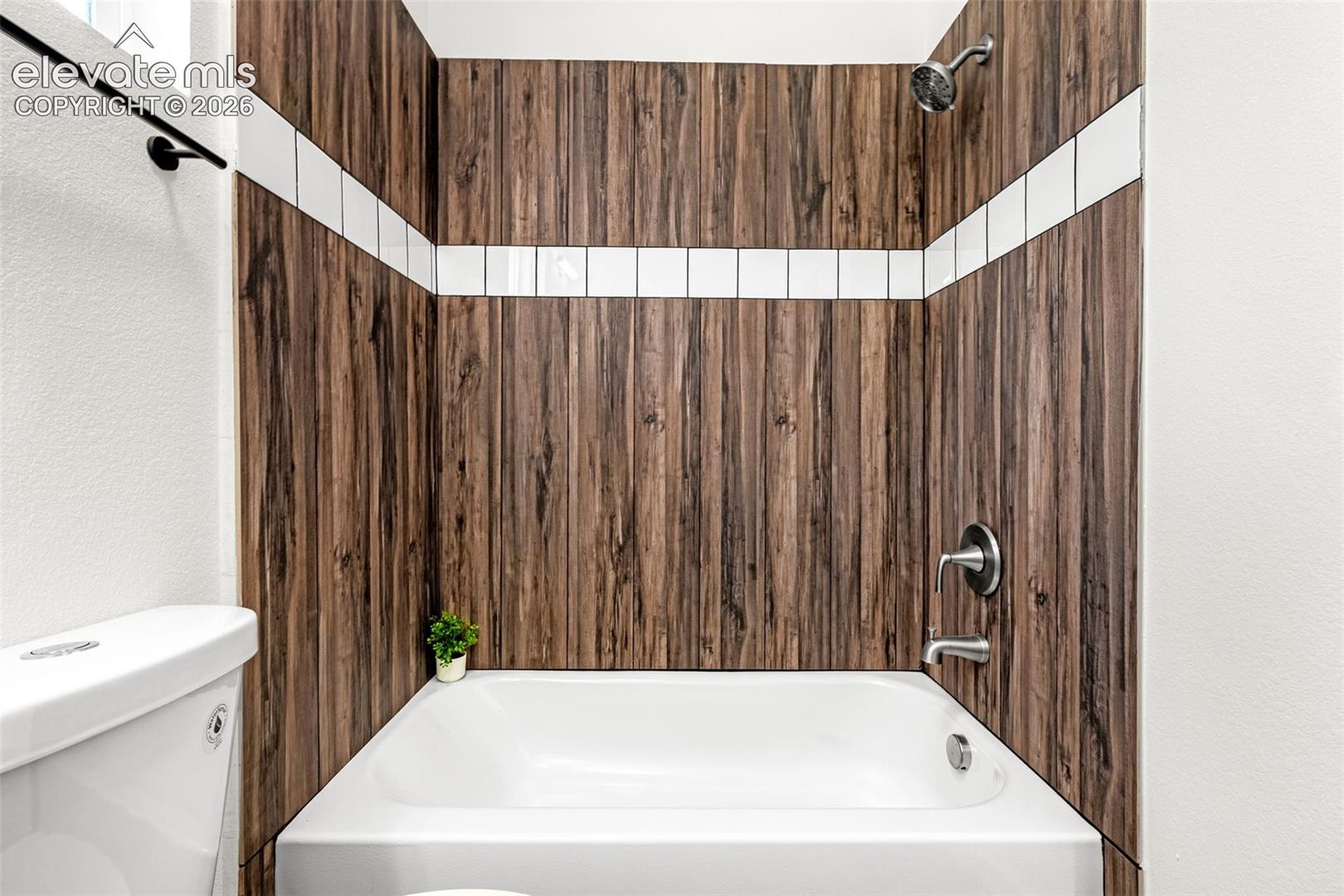 Bathtub with wood-finish tile surround and white accent stripe