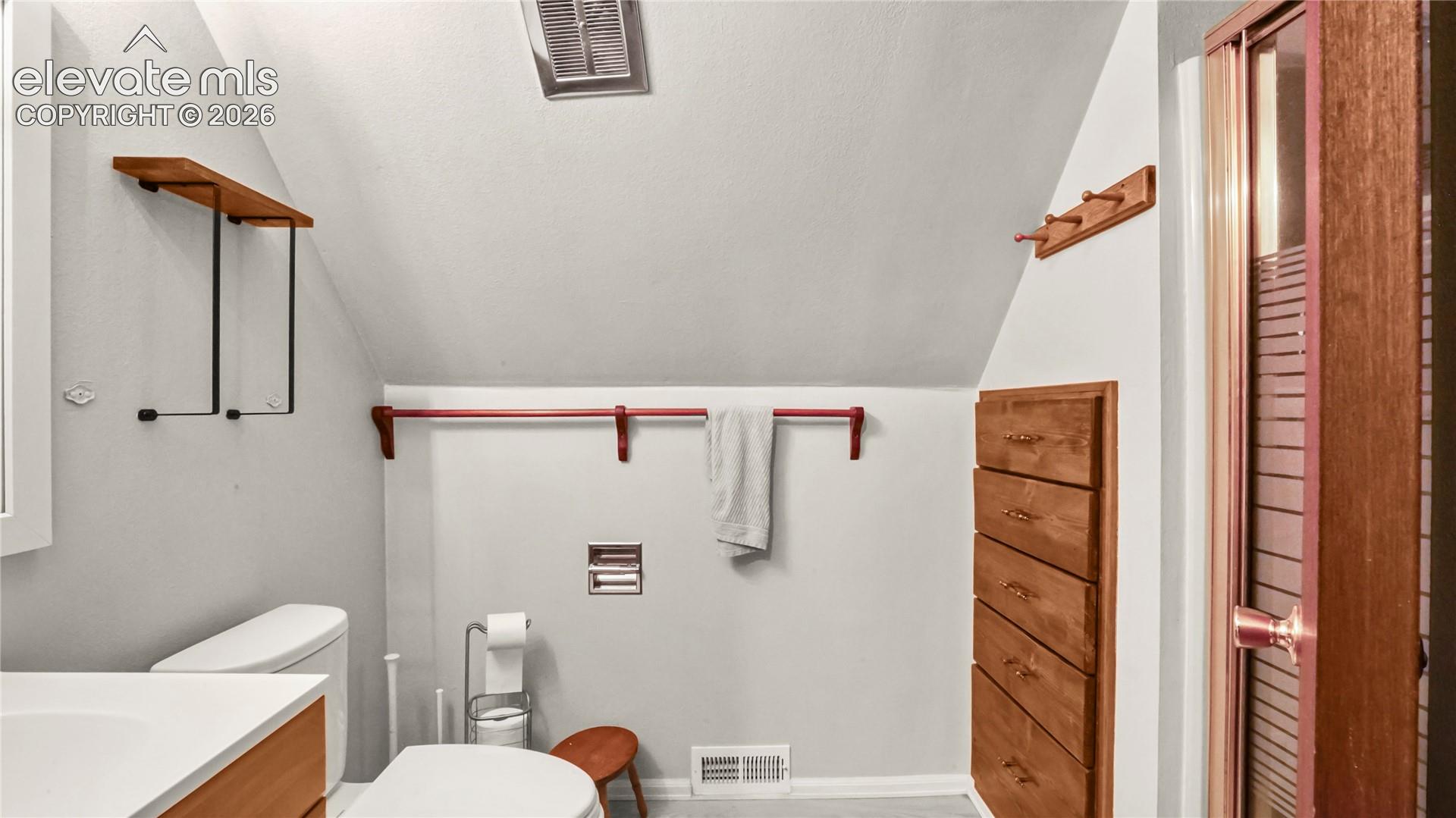 Upstairs bathroom, with vanity, toilet and shower, angled ceiling with a recessed vent, built-in wooden shelving, and a built-in wooden drawer unit, LVP flooring.