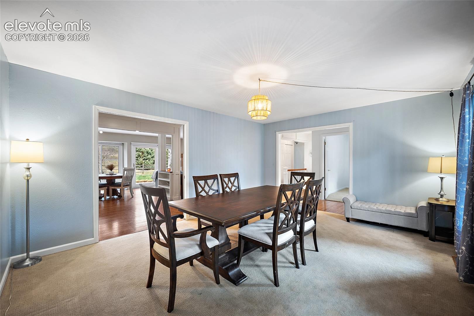 Interior space featuring neutral wall-to-wall carpeting, recessed and overhead pendant lighting, and wide arched doorways