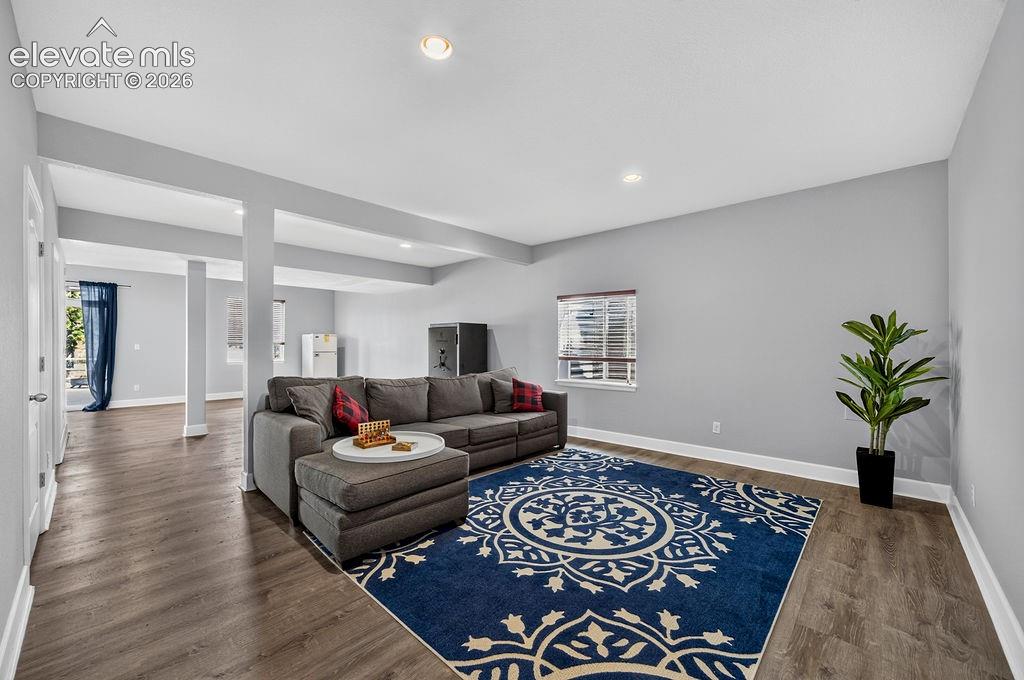 Recessed lighting illuminates the open-concept living space, featuring wood-finish flooring and neutral gray walls