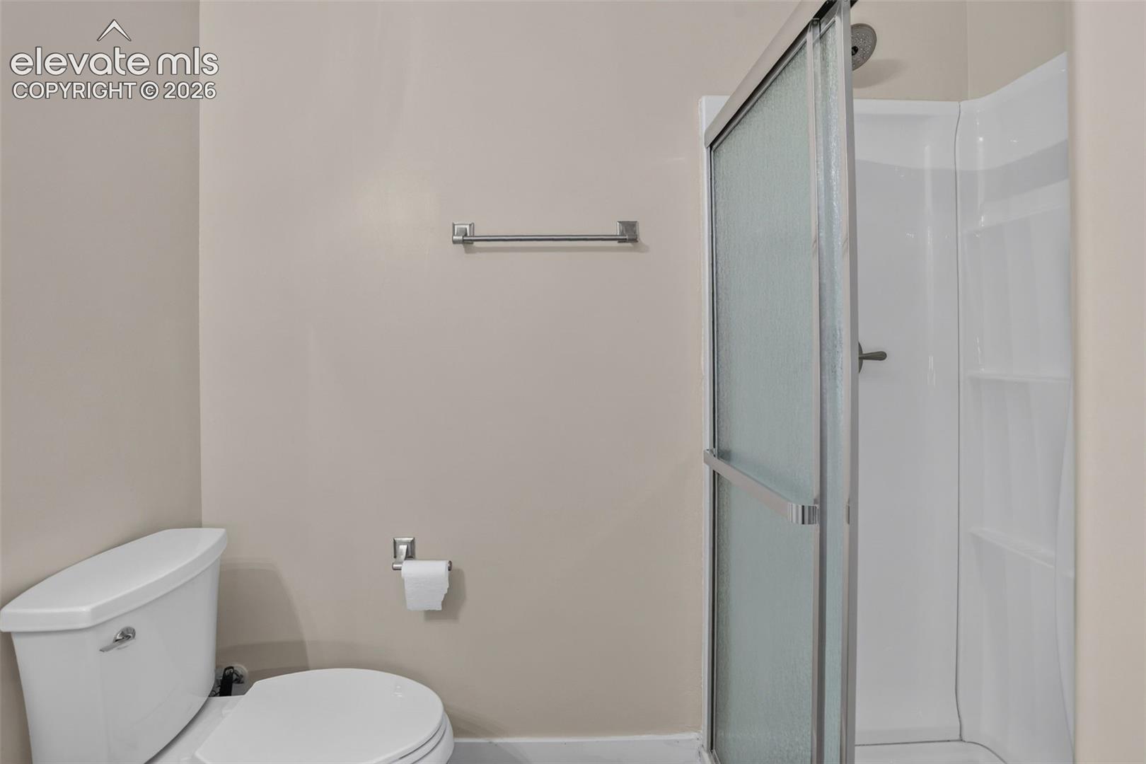 Walk-in shower with a framed glass door, white shower surround, and integrated shelving