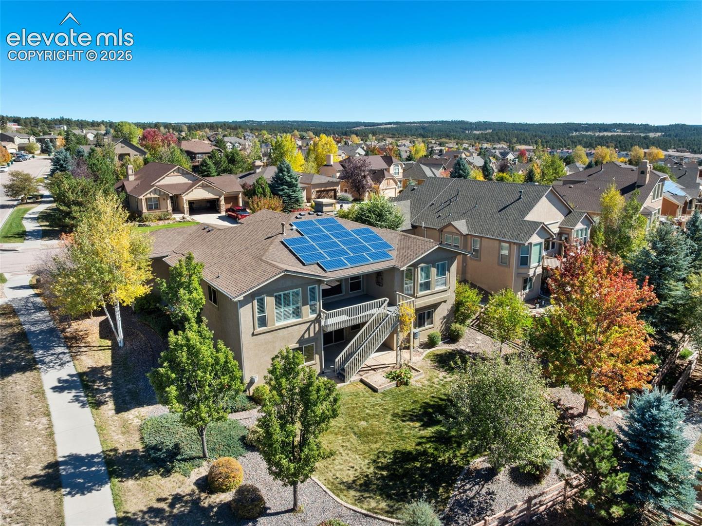 AERIAL VIEW OF BACK OF HOME  FEATURING SOLAR ON ROOF, BEAUTIFUL MATURE TREES AND WALKING TRAIL