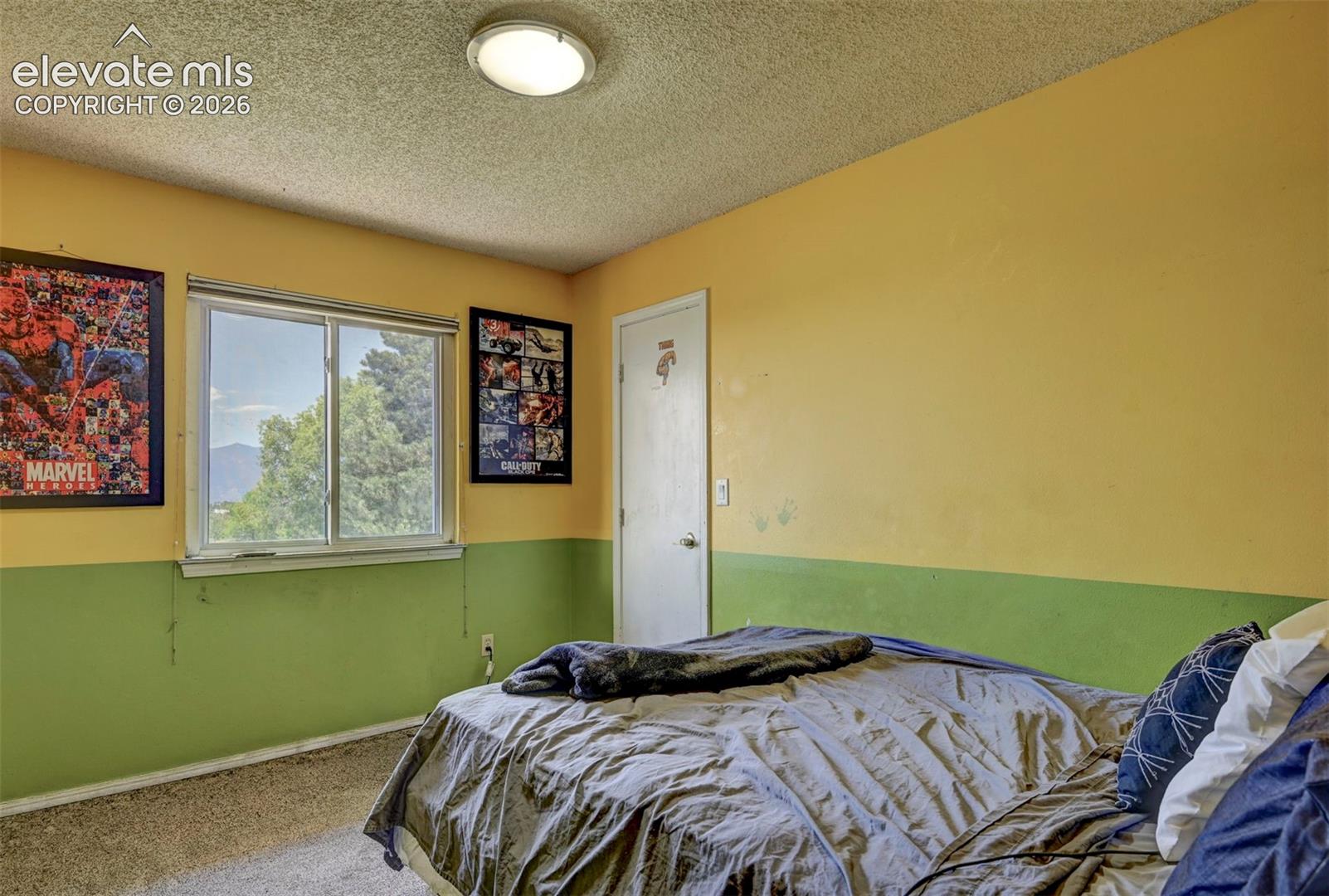 Interior room featuring a large window, textured ceiling, and a flush-mount ceiling light fixture
