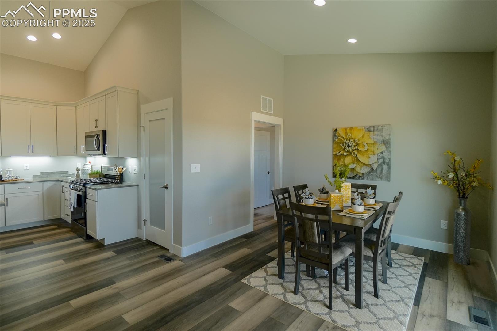 Dining area featuring LTV wood-type flooring and high vaulted ceiling