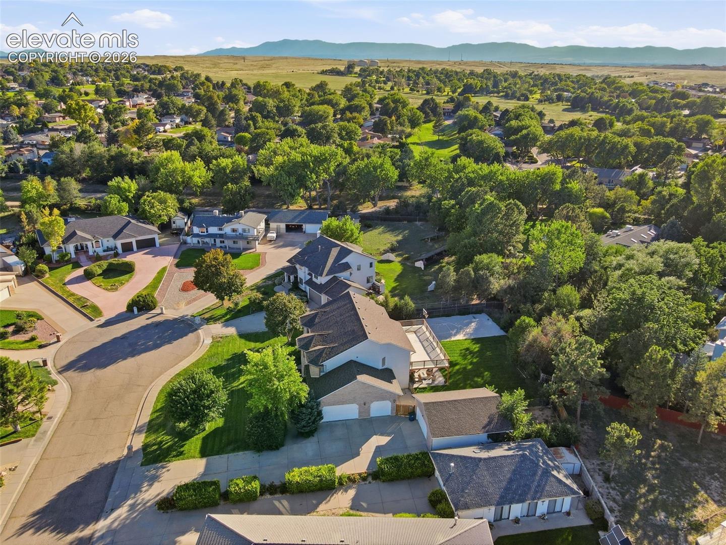 Suburban setting with mature trees, paved streets, and residential homes