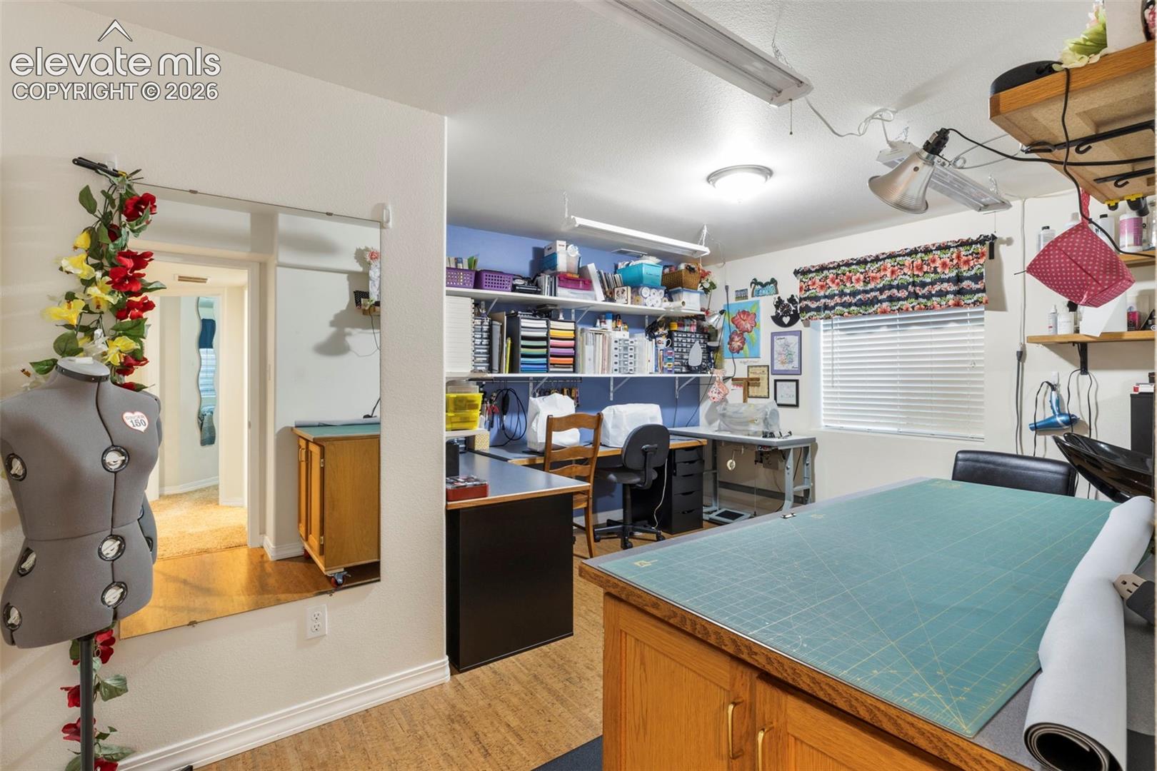 Room featuring wood-finish flooring, a window with blinds, and built-in shelving