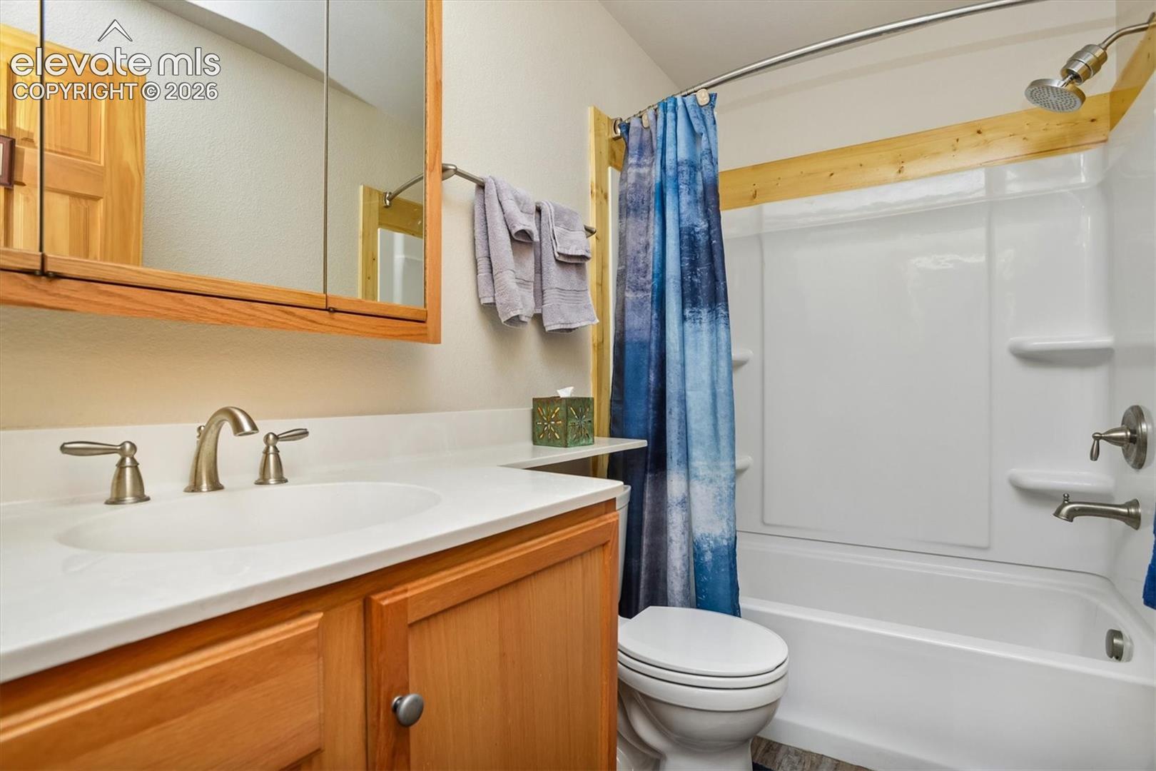 Bathroom featuring a white integrated sink, brushed nickel faucet, and a light wood-finish vanity with cabinet storage